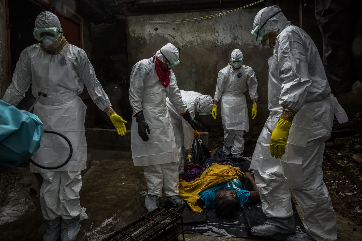 Members of a Liberian Red Cross burial team, under contract from the Liberian Ministry of Health, remove the body of a suspected Ebola victim Lorpu David, 30 on Sept. 18, 2014 in the Gurley street community in central Monrovia, Liberia.