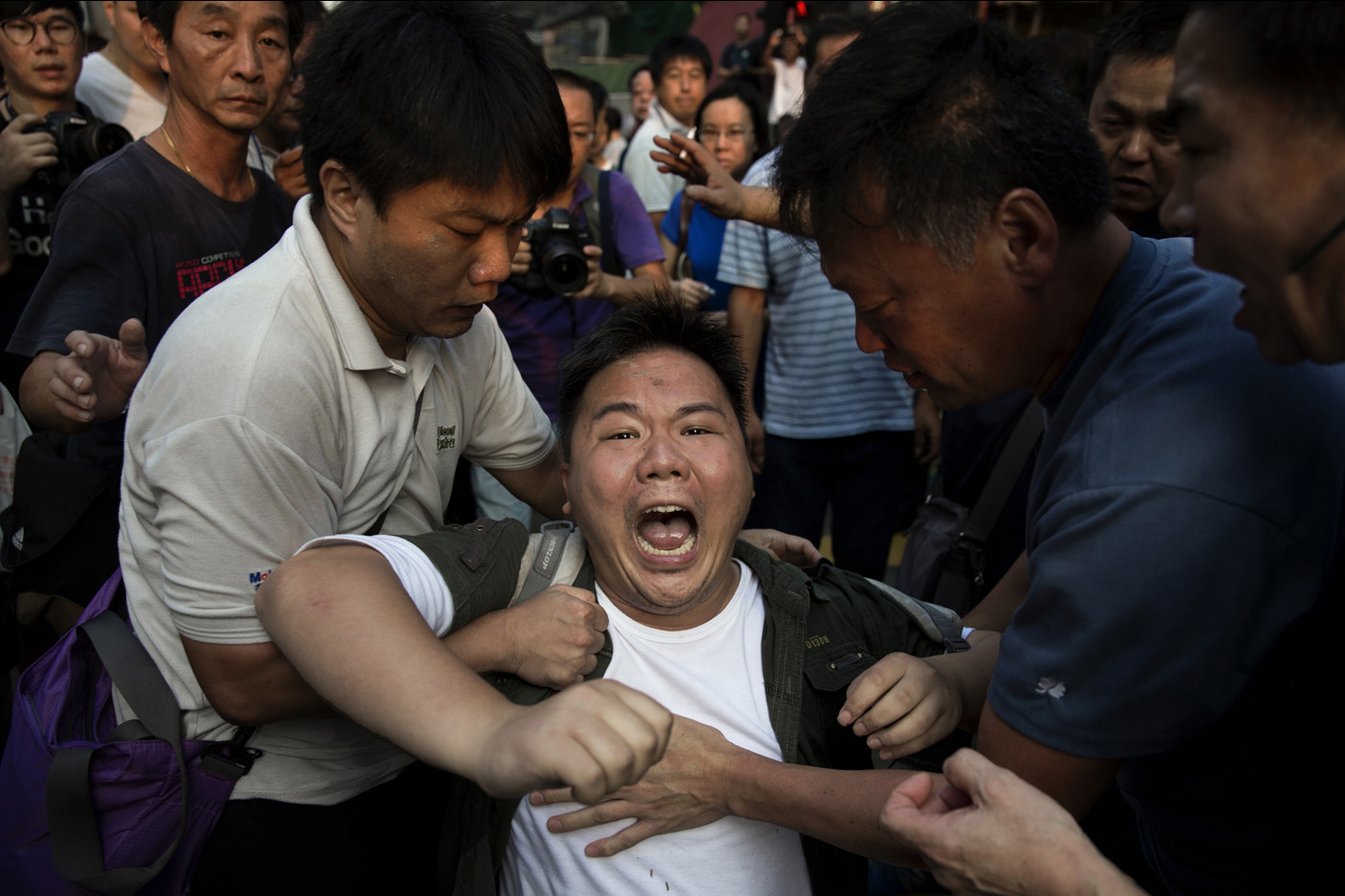 A pro-democracy protestor yells as he is attacked by an anti occupy crowd during democracy demonstrations in the Mong Kong district of Hong Kong.