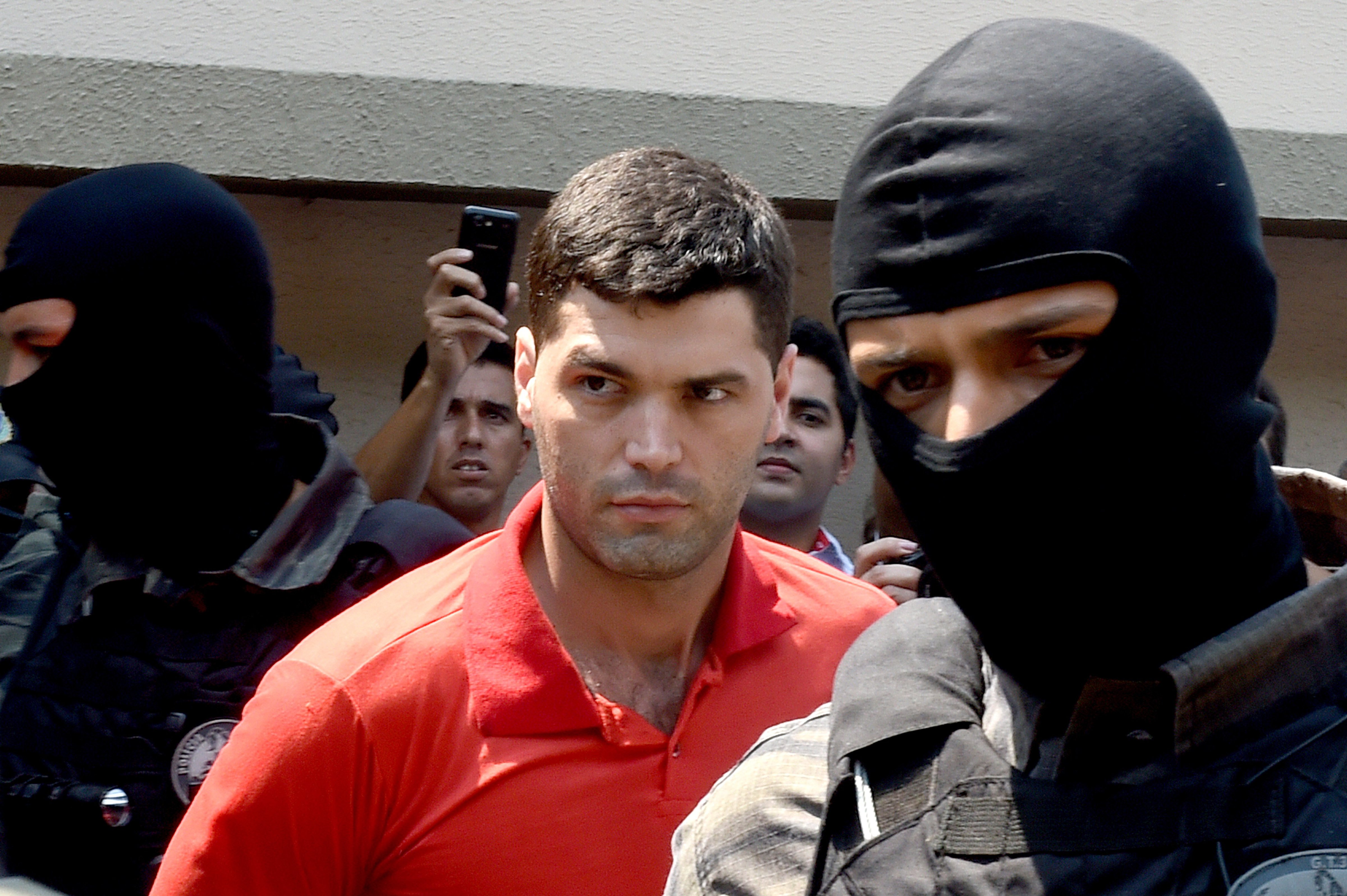 Alleged serial killer Tiago Gomes da Rocha, center, suspected of killing 39 people, is escorted by police officers at the Department of Security, a day after his arrest, in Goiania, state of Goias, Brazil, on Oct. 16, 2014. (Evaristo Sa—AFP/Getty Images)
