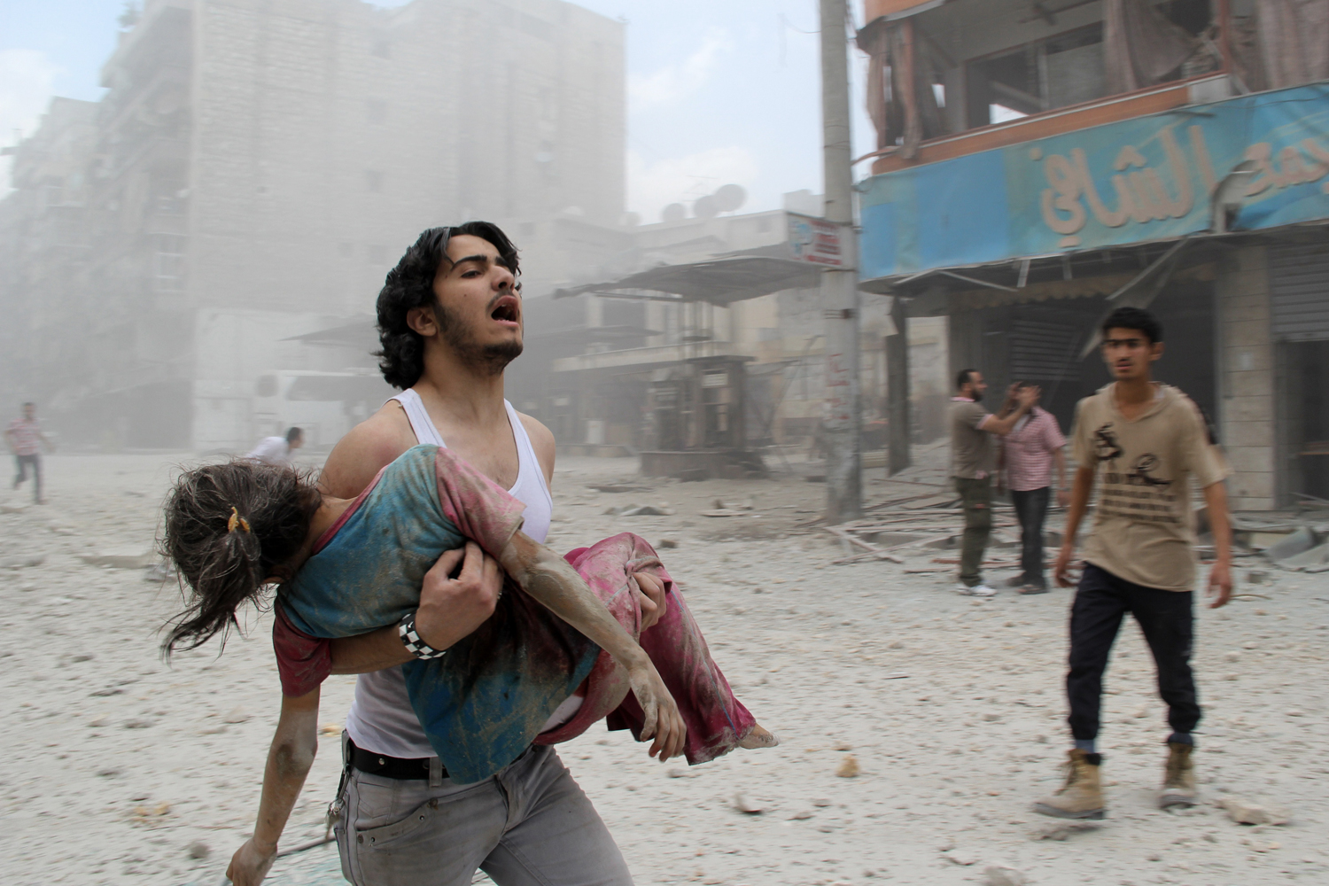 A man carries a young girl who was injured in a reported barrel-bomb attack by government forces on June 3, 2014 in Kallaseh district in the northern city of Aleppo, Syria.