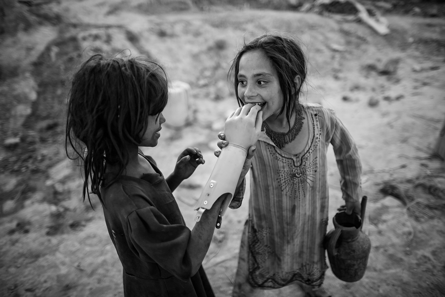 Two Afghan girls play with an artificial hand, south of Kabul.