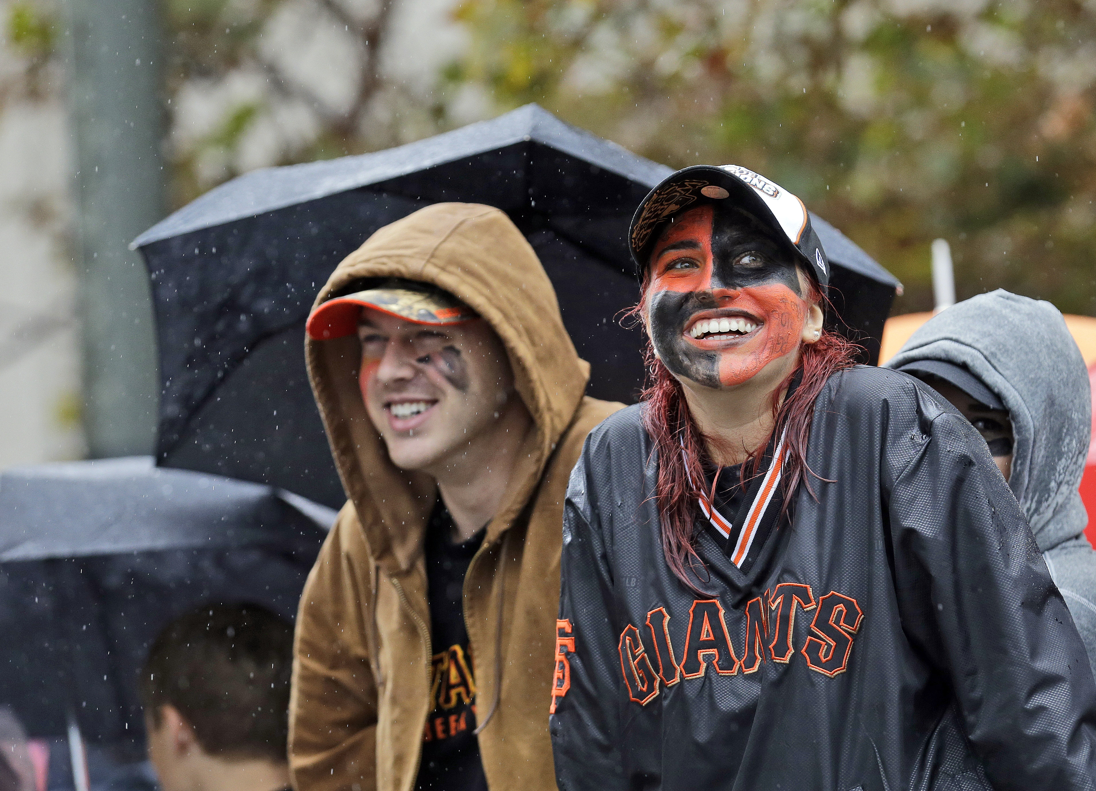 San Francisco Giants baseball fans Megan McPhillips, right, and Travis Saracco from Santa Rosa, Calif., wait in the rain for the start of the victory parade for the 2014 World Series Champion San Francisco Giants on Friday, Oct. 31, 2014 in San Francisco. (Jeff Chiu—AP)