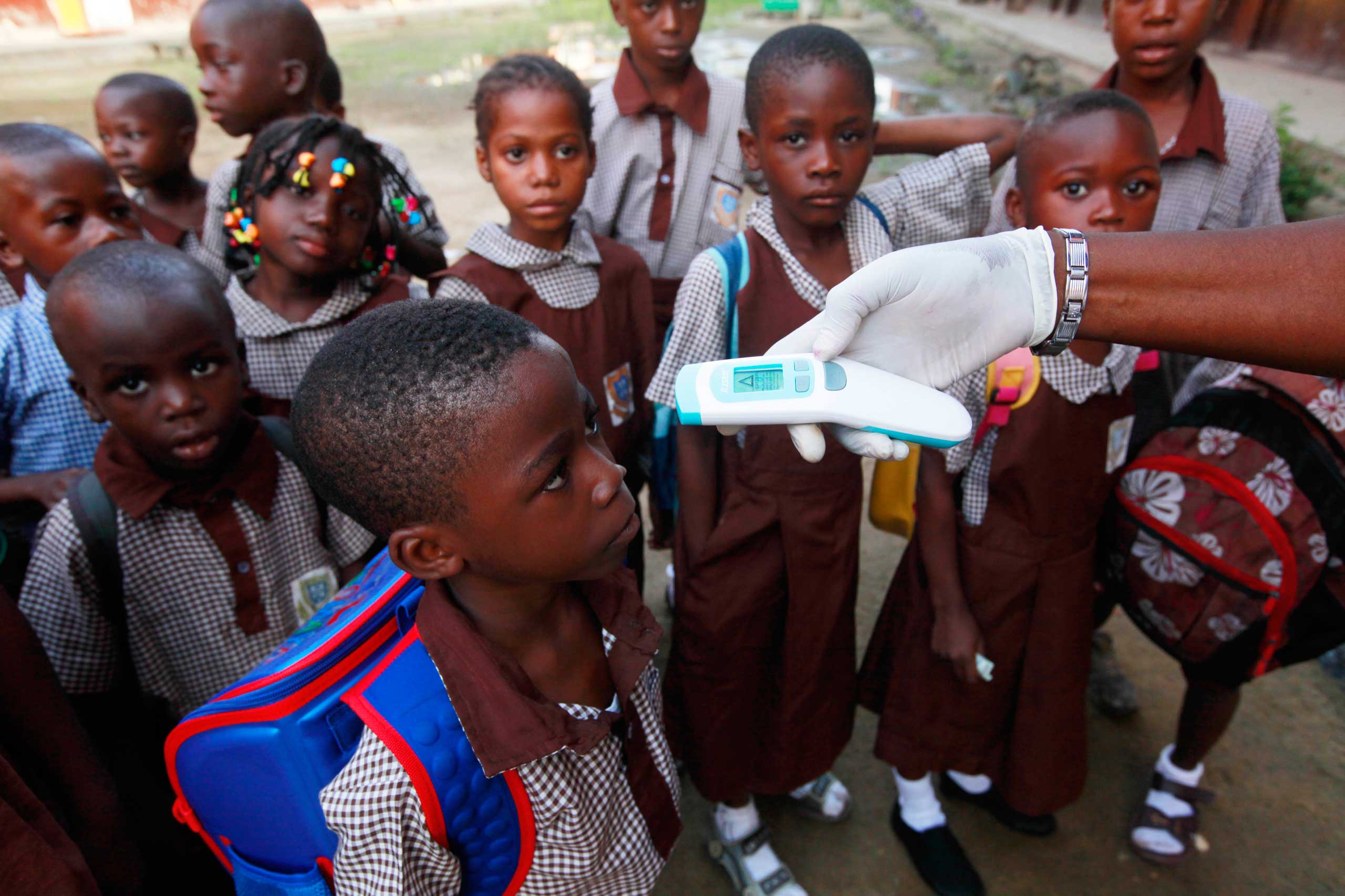 A teacher uses a thermometer to test students' temperature to check for symptoms of Ebola at Aiyetoro African Church Nursery and Primary school in Lagos, Nigeria, Oct. 8, 2014. (Sunday Alamba—AP)