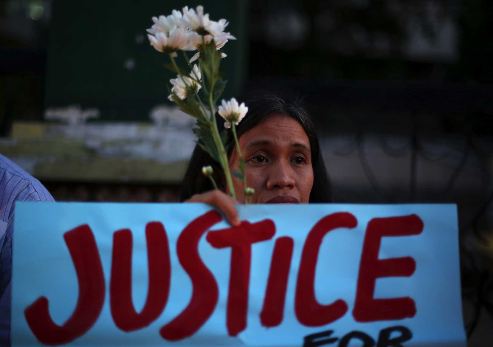 A Filipino activist holds flowers and a slogan during prayers in suburban Quezon city, Philippines on Thursday Oct. 23, 2014, to call for justice for the killing of Filipino transgender Jeffrey "Jennifer" Laude. (Aaron Favila—AP)