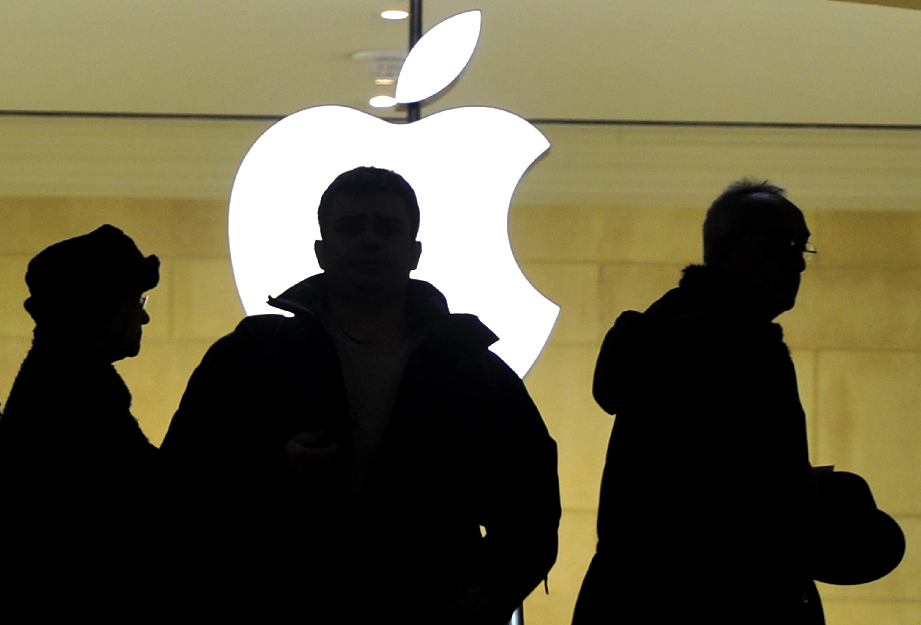 People walk past the Apple logo at the Apple Store at Grand Central Terminal in New York.