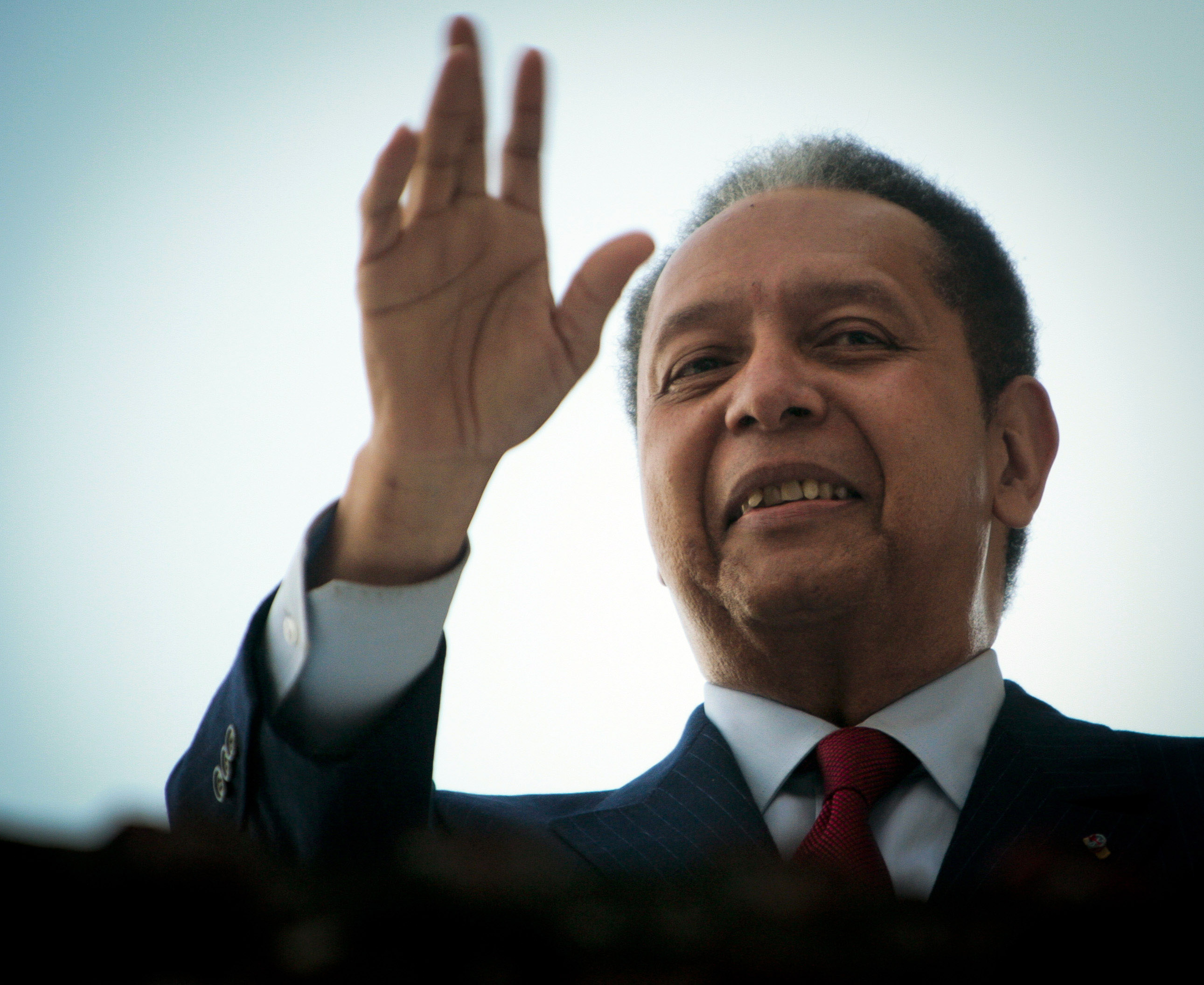 Former leader of Haiti Jean-Claude "Baby Doc" Duvalier waves from a balcony following a press conference at his house in Petionville January 21, 2011 in Port-au-Prince, Haiti. (Lee Celano—Getty Images)