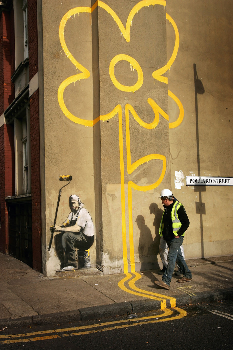 Builders walk past a Banksy on Pollard Street on November 1, 2007 in London, England.