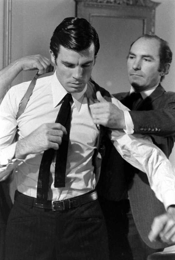 Director Peter R. Hunt helps Robert Campbell get into a shoulder holster, 1967.