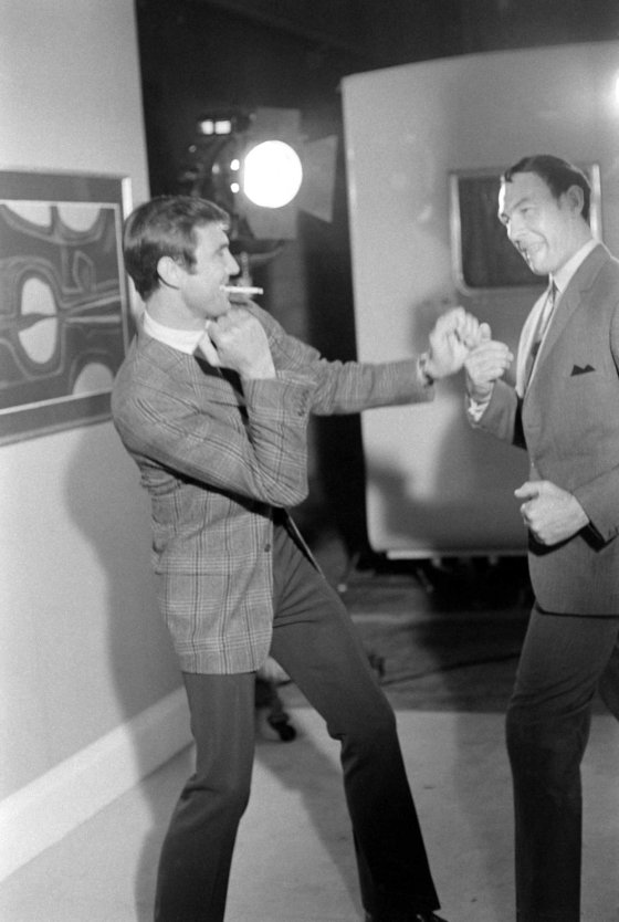 George Lazenby goofs off behind the scenes of his screen test, boxing with an unidentified man, 1967.