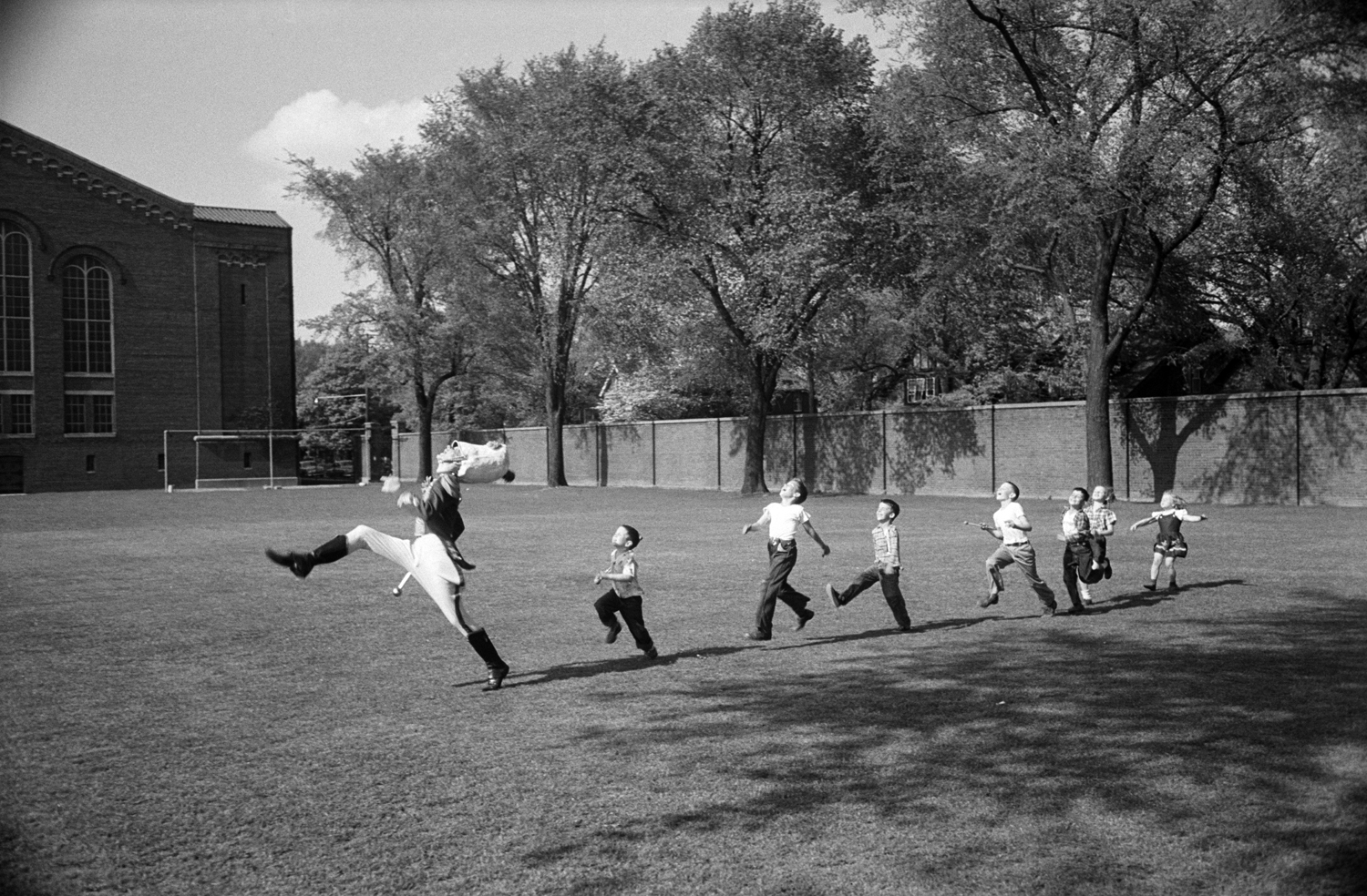 The drum major for the University of Michigan marching band high-steps as children follow suit, 1950.