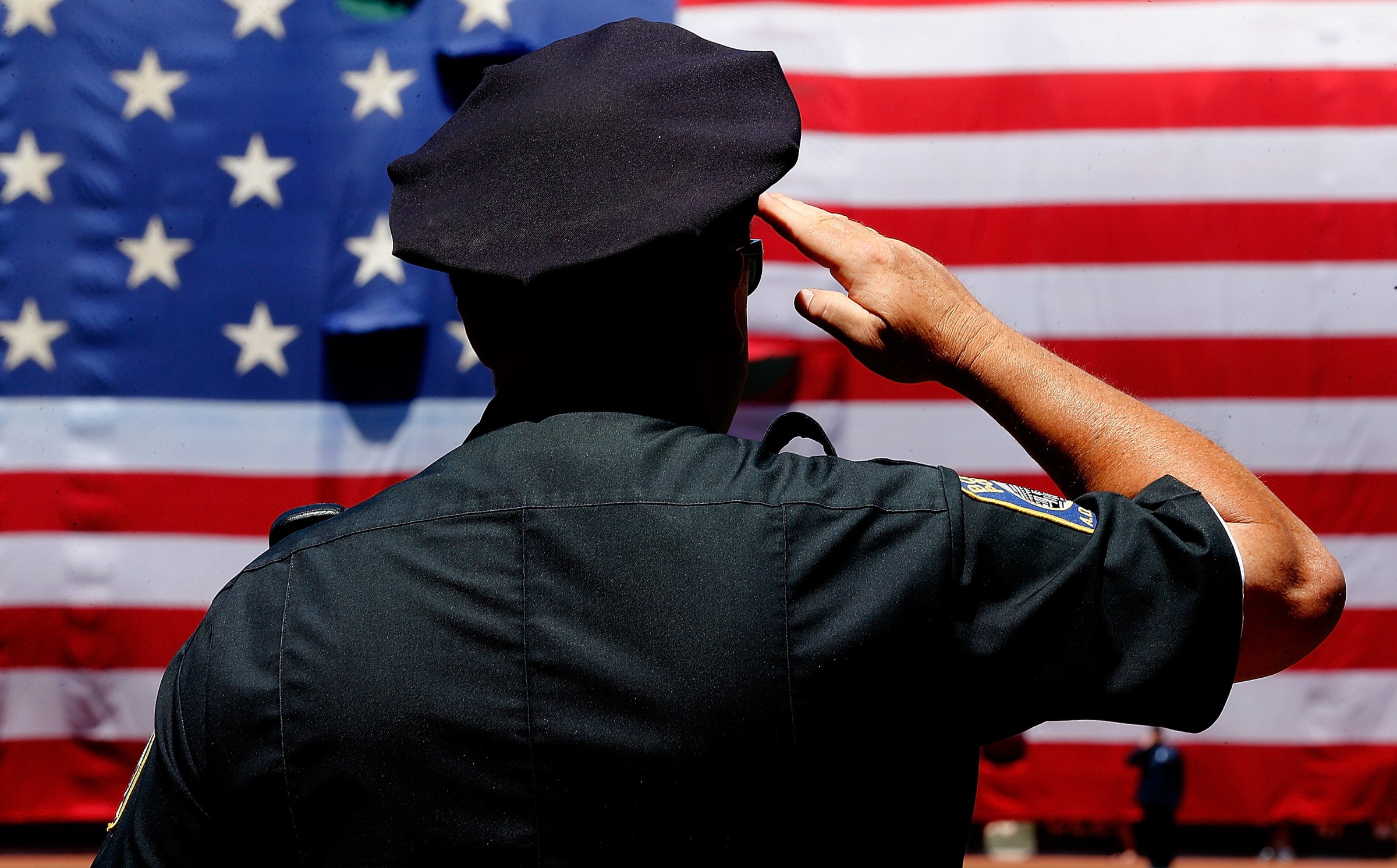A police officer salutes during the National Anthem before the first game of a doubleheader between the Baltimore Orioles and the Boston Red Sox at Fenway Park on July 5, 2014 in Boston.