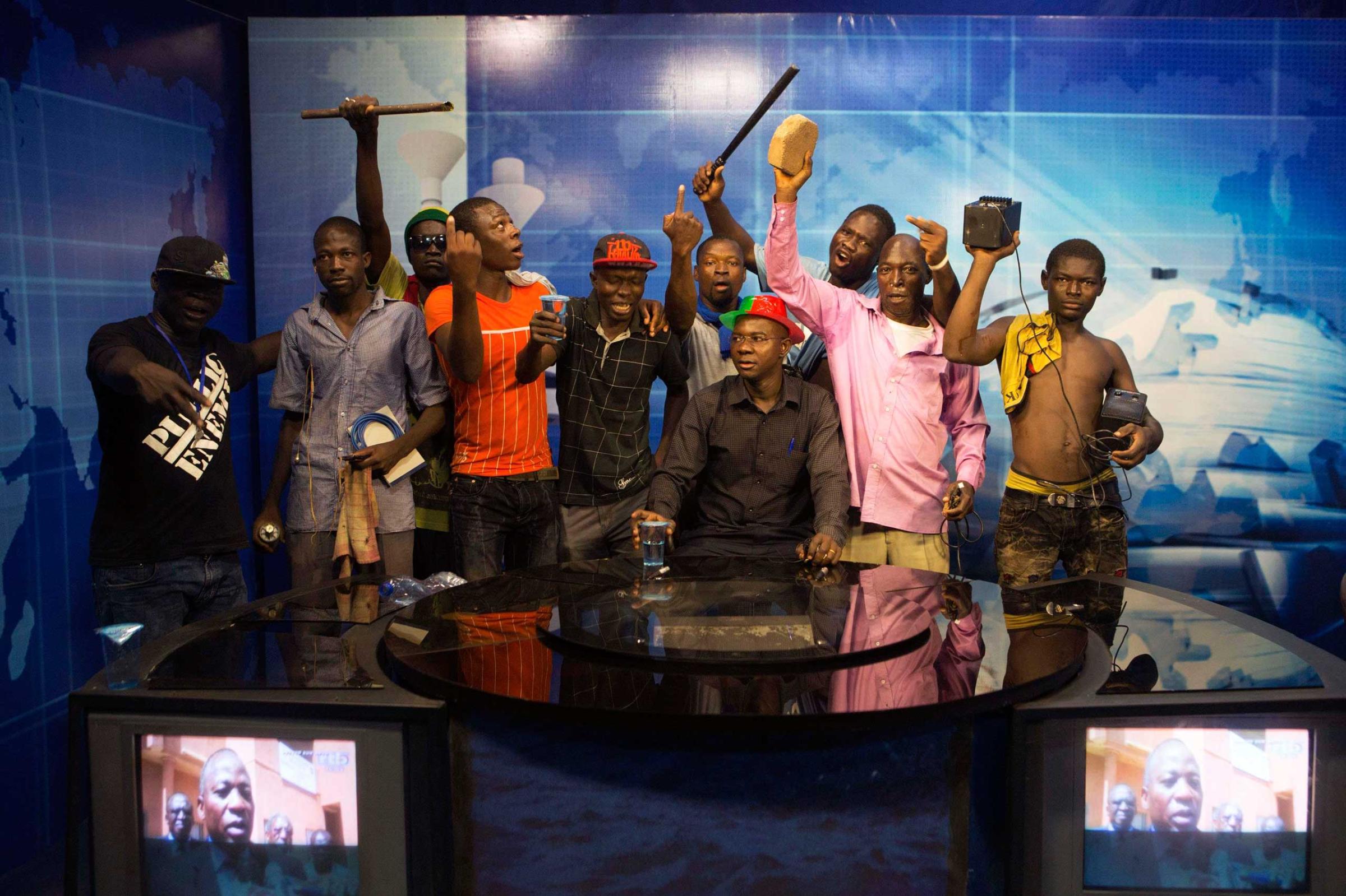 Anti-government protesters take over the state TV podium in Ouagadougou, capital of Burkina Faso, Oct. 30, 2014.