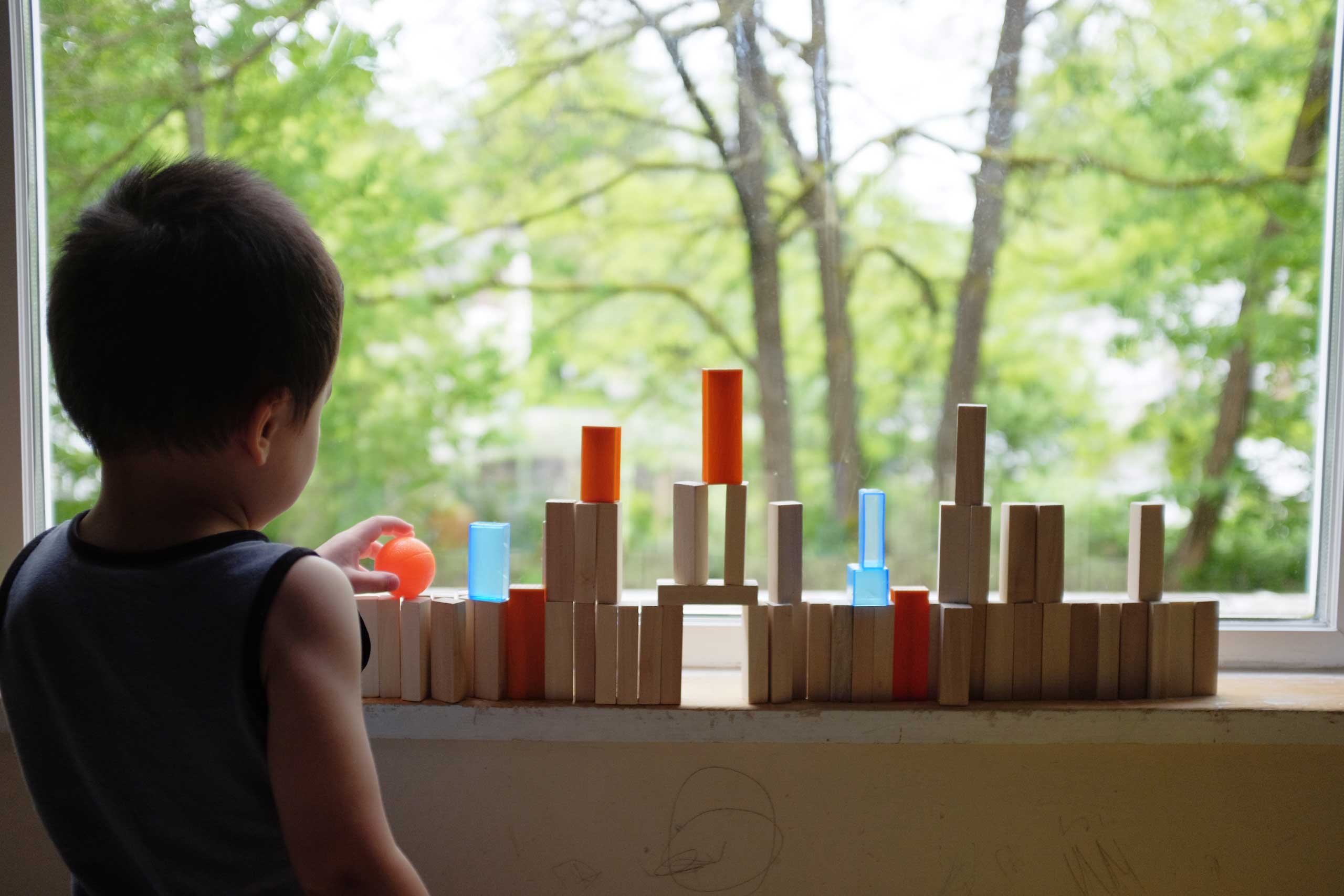 Child building tower with blocks on window sill