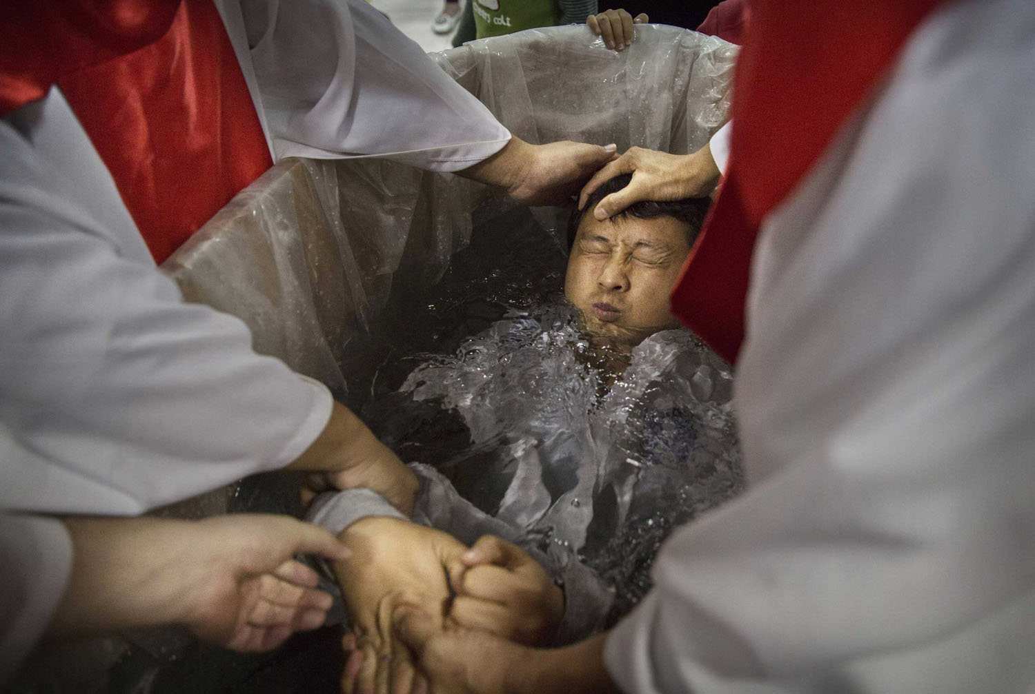 A new Chinese Christian man is dunked in the water in a small tub as he is baptized during a ceremony at an underground independent Protestant Church on Oct. 12, 2014 in Beijing, China.