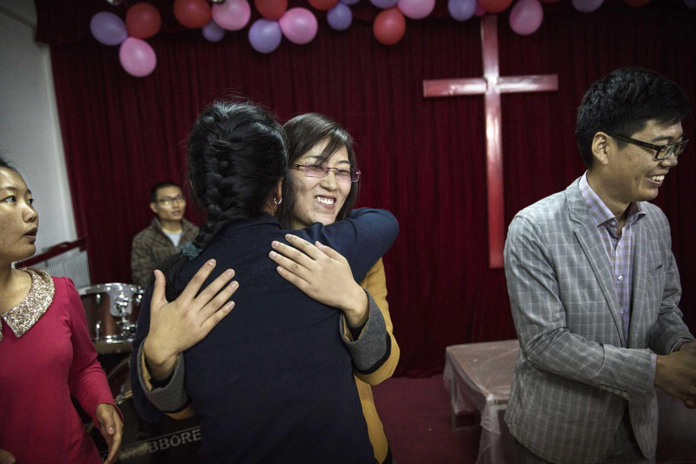 A woman is embraced by another member of the congregation as she is acknowledged for attending for the first time during a service at an underground independent Protestant Church in Beijing.