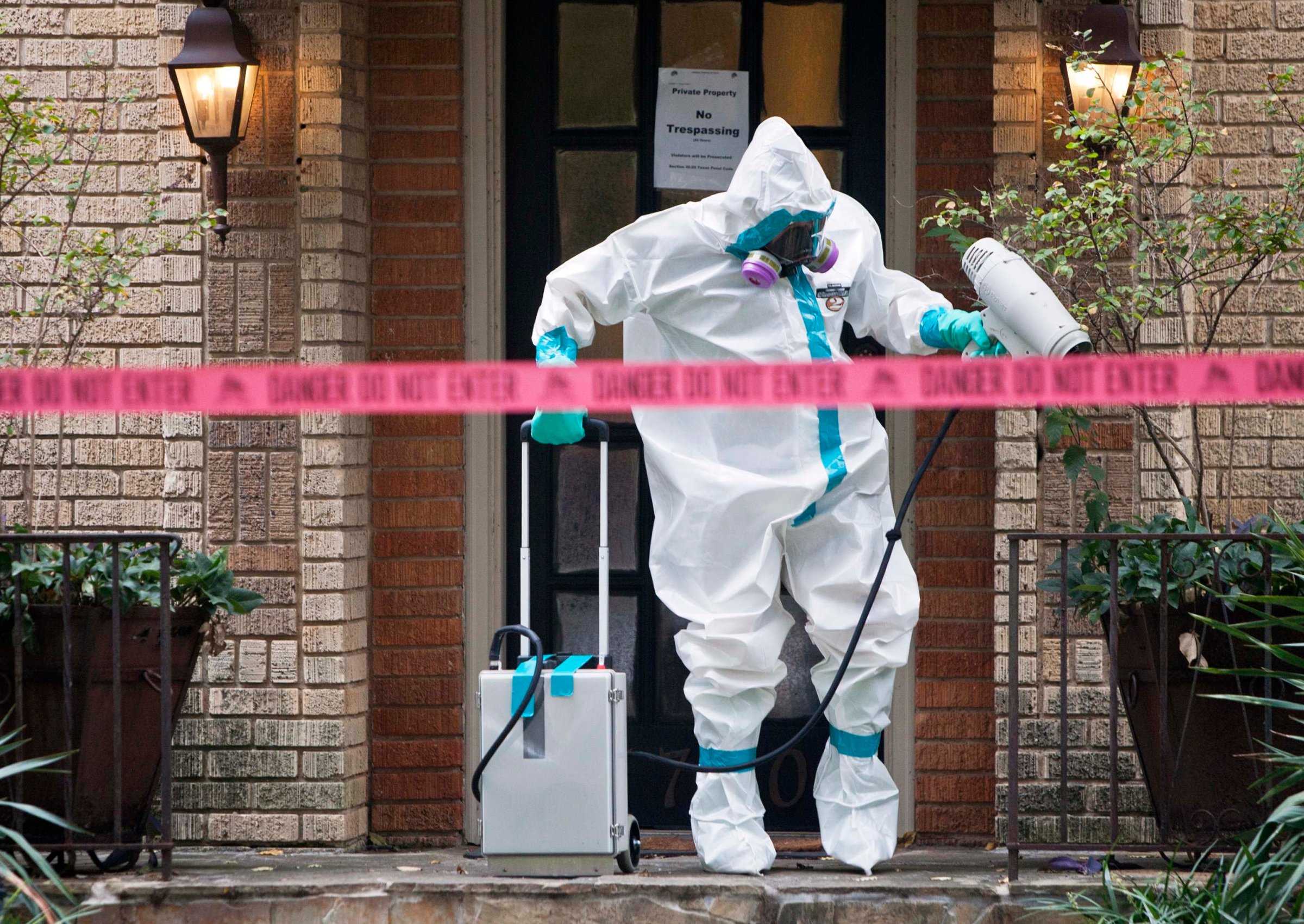 A member of the CG Environmental HazMat team disinfects the entrance to the residence of a health worker at the Texas Health Presbyterian Hospital who has contracted Ebola in Dallas on Oct. 12, 2014.
