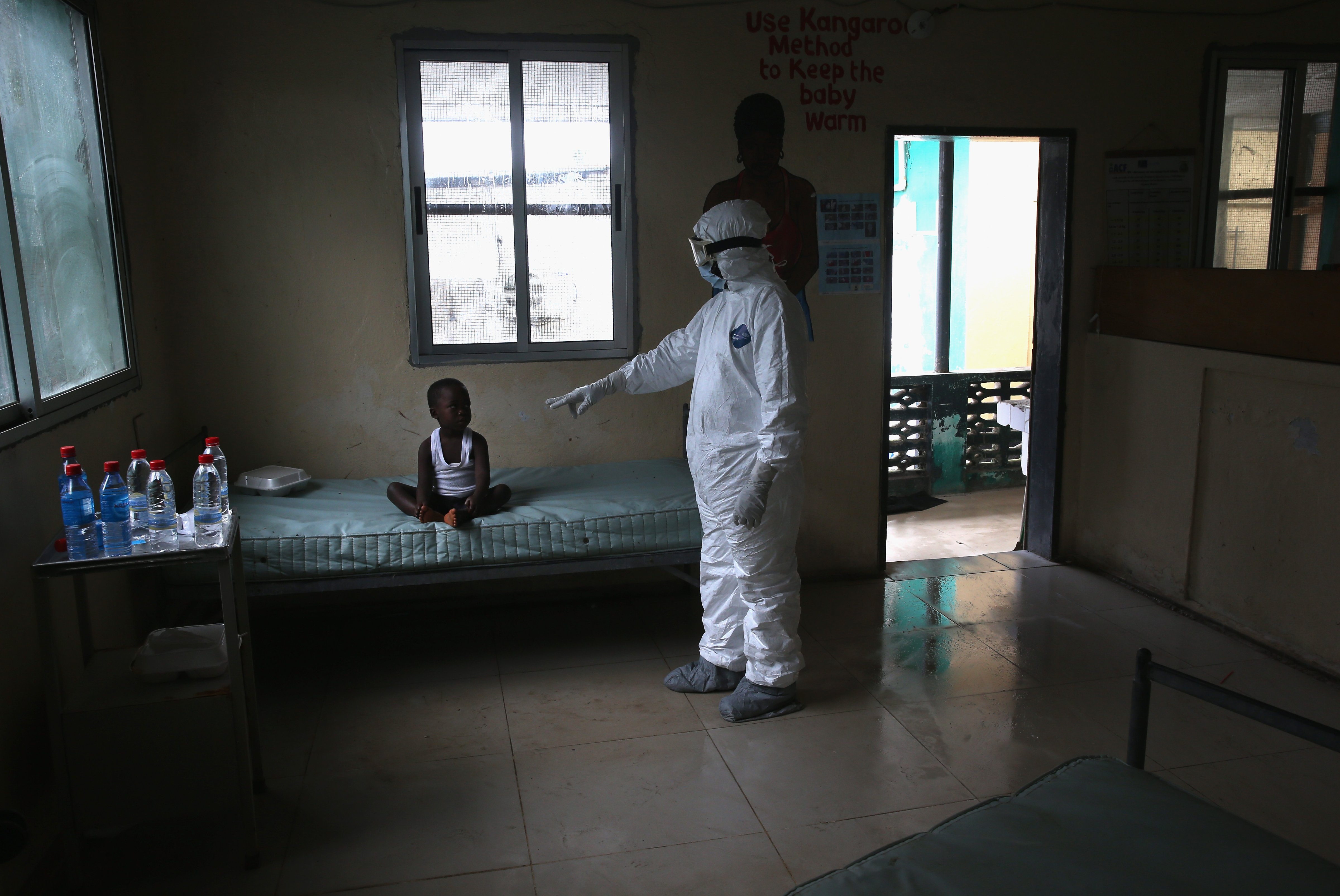 A Liberian Ministry of Health worker, dressed in an anti-contamination suit, speaks to Banu, 4, in a holding center for suspected Ebola patients at Redemption Hospital on October 3, 2014 in Monrovia, Liberia. (John Moore—Getty Images)