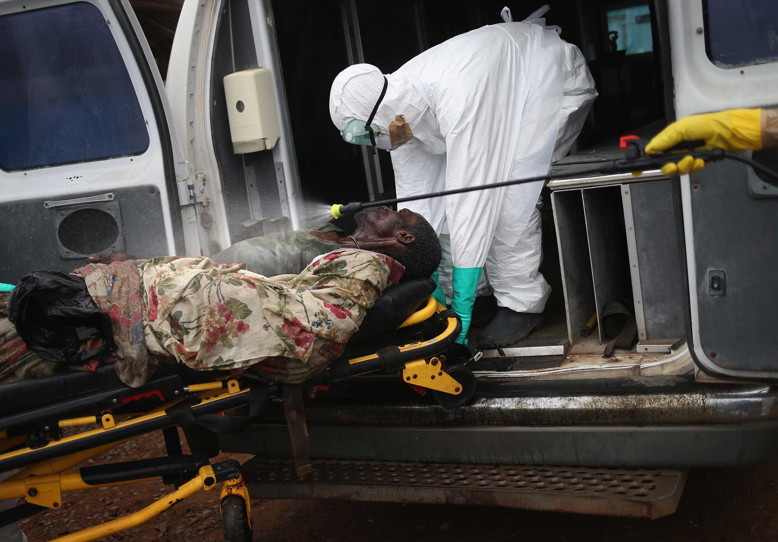 A burial team disinfects an Ebola victim while collecting him for cremation on Oct. 2, 2014 in Monrovia, Liberia. (John Moore—Getty Images)