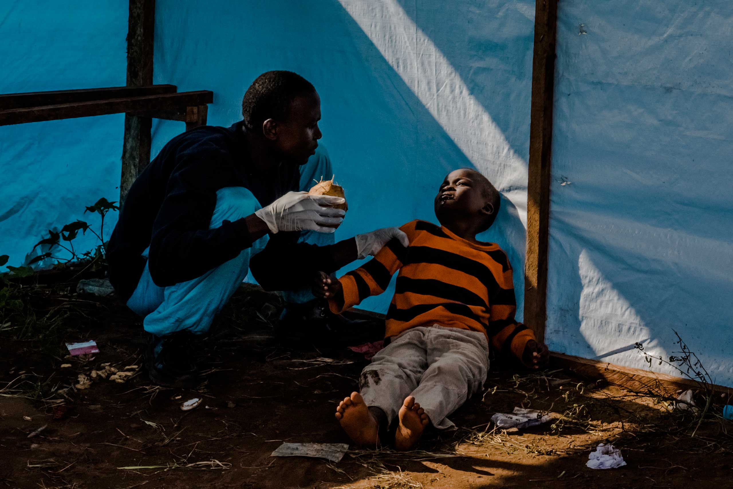 James Dorbor, 8, suspected to have Ebola, lays on the ground as his father Edward tried to get the boy to drink coconut water. They waited for James to be admitted into the JFK Ebola treatment center on Sept. 5, 2014 in Monrovia, Liberia.