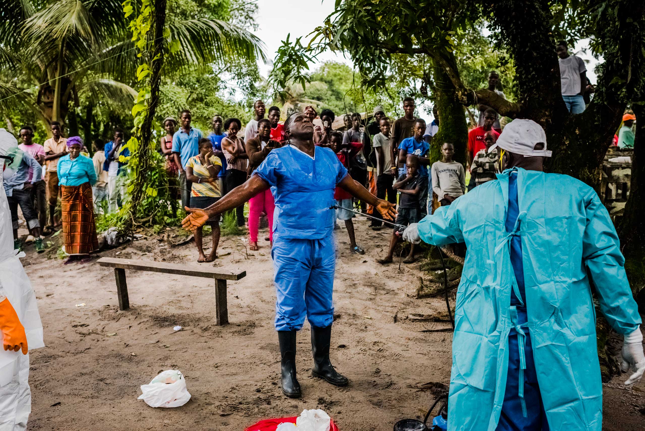 A member of a Liberian Red Cross burial team is disinfected, with chlorine sprayed on by a colleague, after having  removed the body of a man, a suspected Ebola victim, on Sept. 6, 2014 in Monrovia, Liberia.
