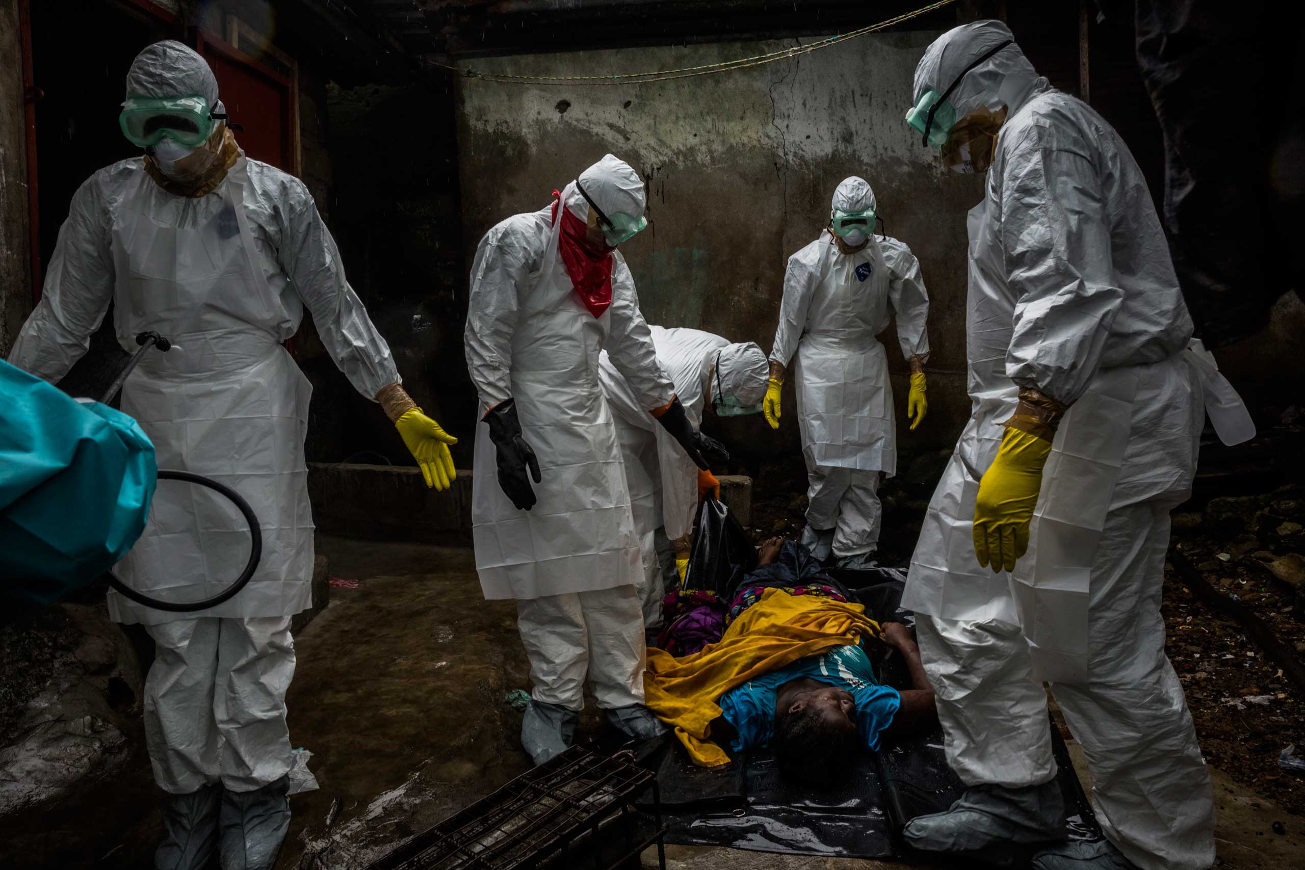 Members of a Liberian Red Cross burial team, under contract from the Liberian Ministry of Health, remove the body of suspected Ebola victim Lorpu David, 30, on Sept. 18, 2014, in the Gurley street community in central Monrovia, Liberia.
