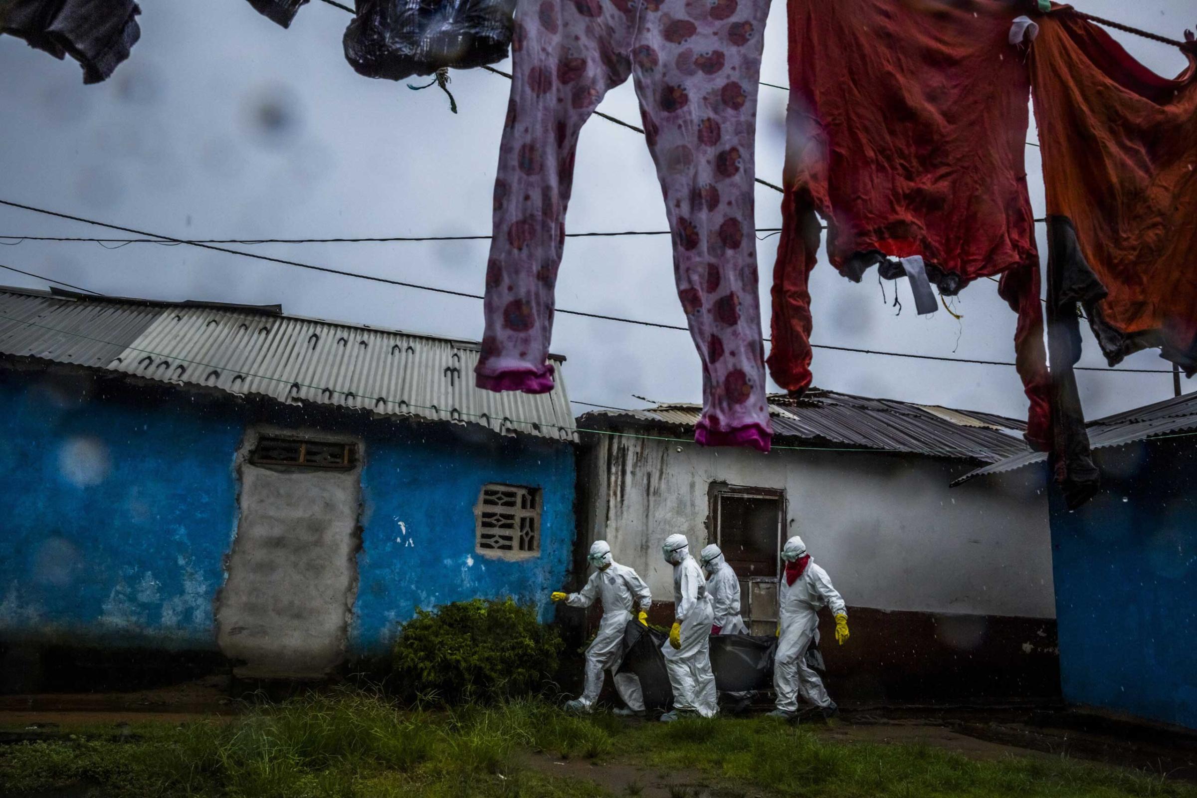 A burial team collects the body of a 75-year-old woman in a neighborhood called PHP in Monrovia, Liberia.