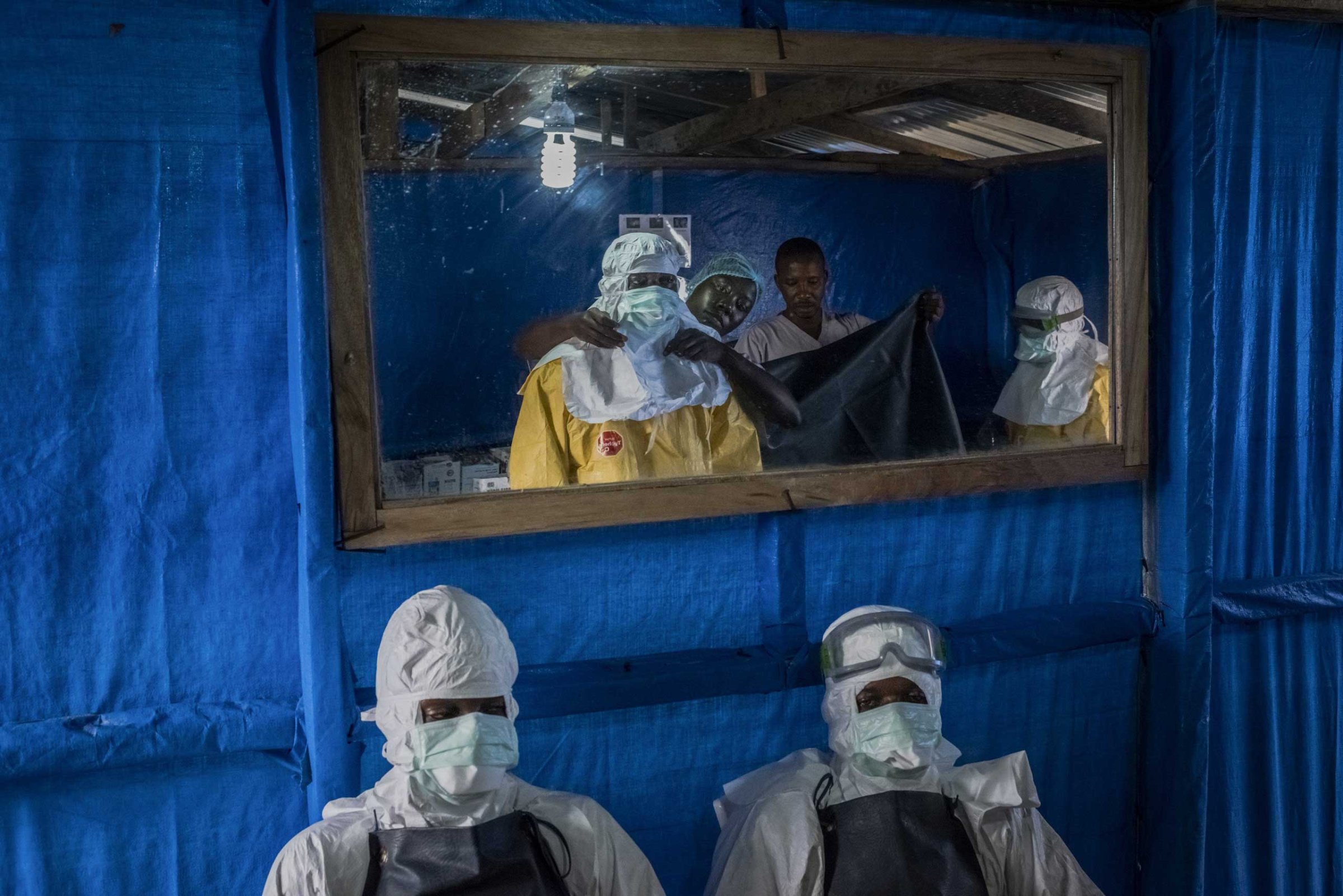 Health workers receive assistance with putting on their protective gear before entering the high-risk zone at the Bong County Ebola Treatment Unit near Gbarnga in rural Bong County, Liberia, Oct. 5, 2014.