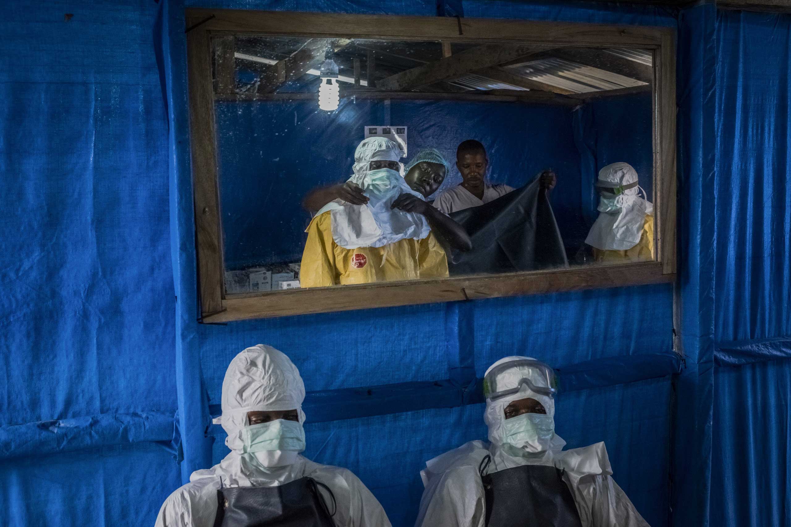 Health workers receive assistance with putting on their protective gear before entering the high-risk zone at the Bong County Ebola Treatment Unit.