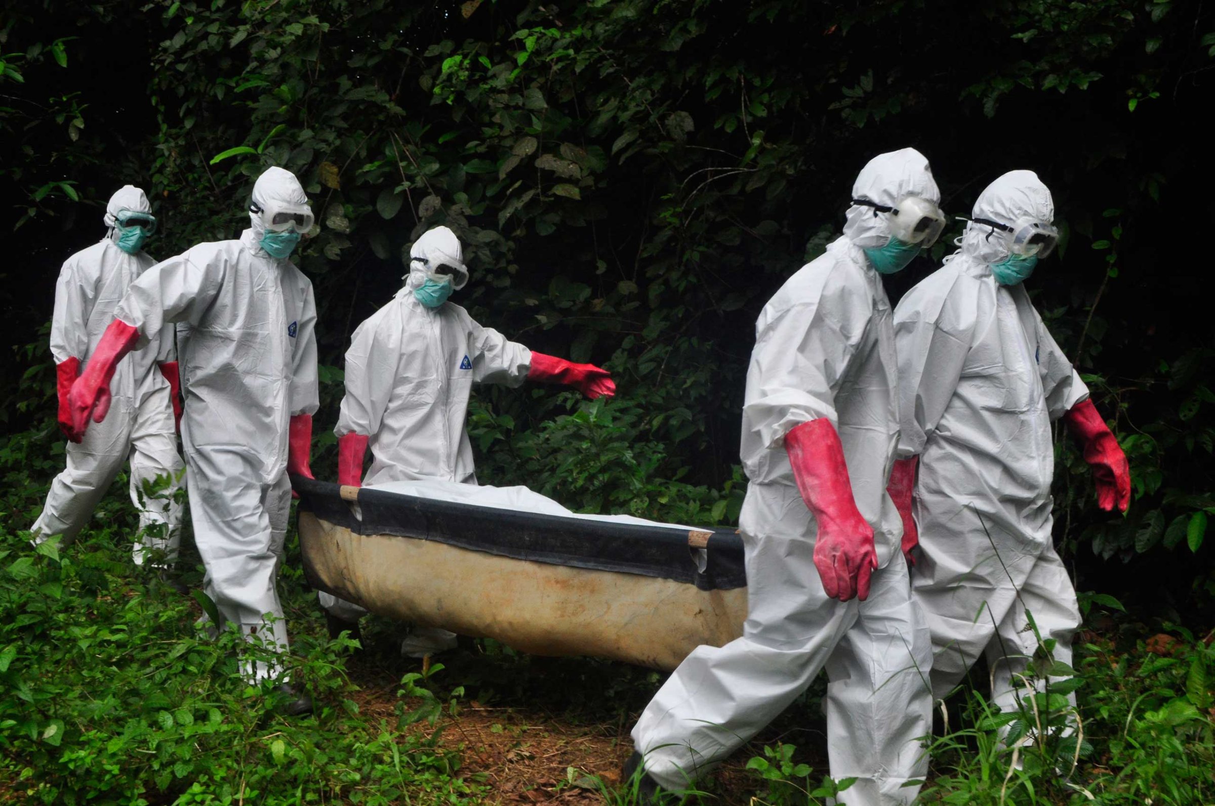 A burial team in protective gear carry the body of woman suspected to have died from the Ebola virus in Monrovia, Liberia, Oct. 18, 2014.