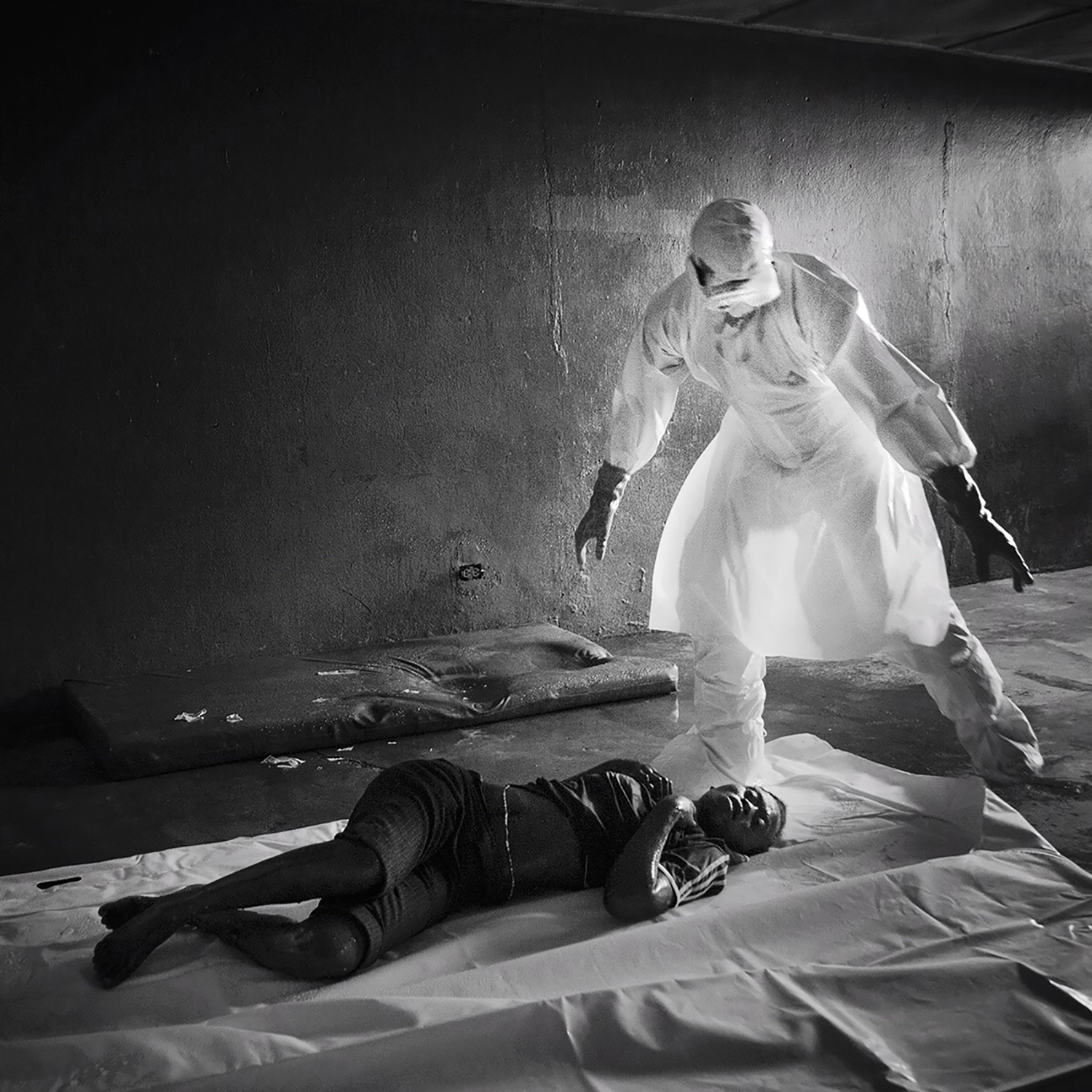 A member of the burial team removes a woman who had died the night before in an Ebola clinic in West Point, Monrovia, Liberia.