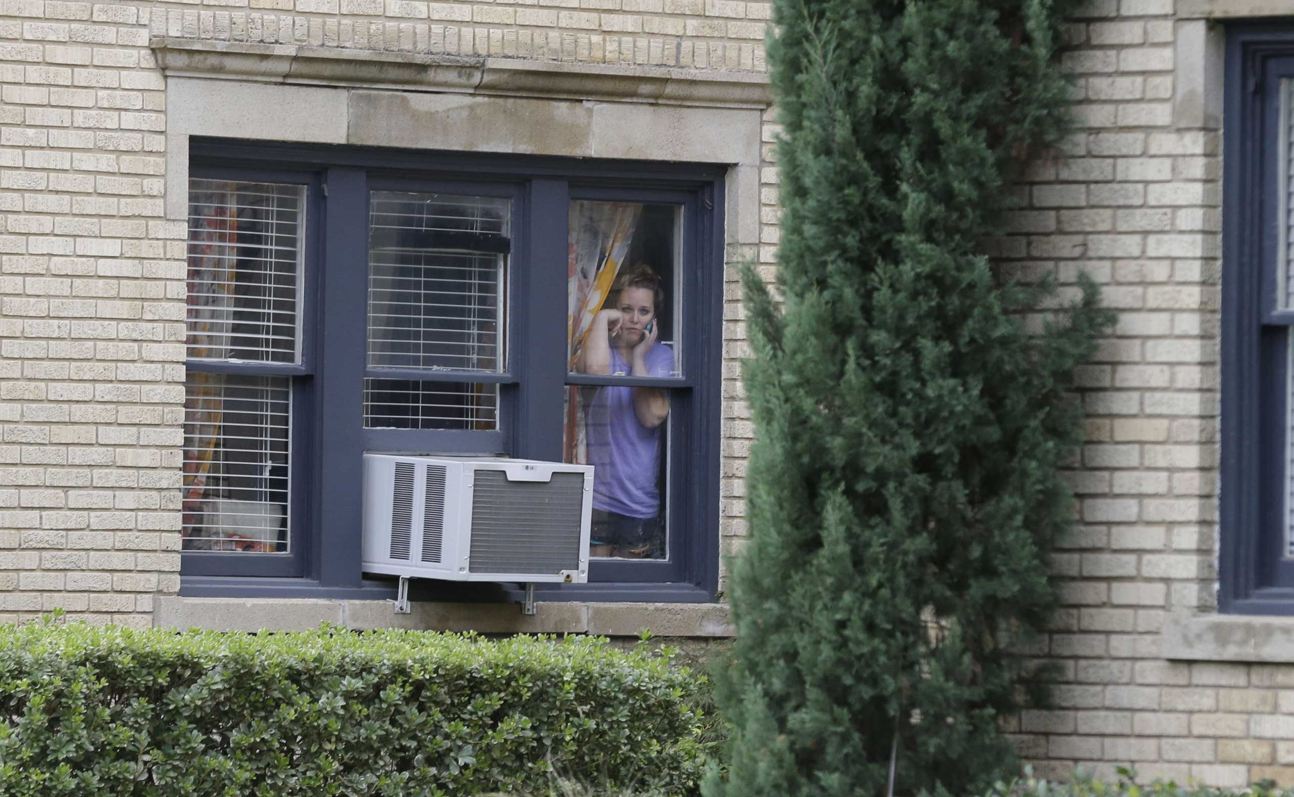 A woman looks out of her window from an apartment building next door to the apartment building of a hospital worker, Sunday, Oct. 12, 2014, in Dallas (Roger Steinman&mdash;AP)