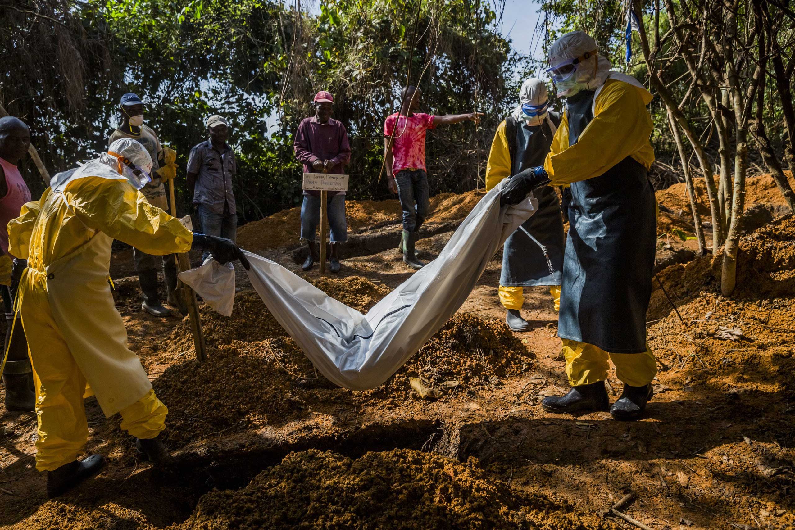Members of a burial team wearing protective gear inter the body of 4-day-old Diana Dormeyan, named for her mother who died shortly after giving birth, at a graveyard adjacent to the Bong County Ebola Treatment Unit near Gbarnga, Liberia, Oct. 8, 2014. (Daniel Berehulak—The New York Times/Redux)