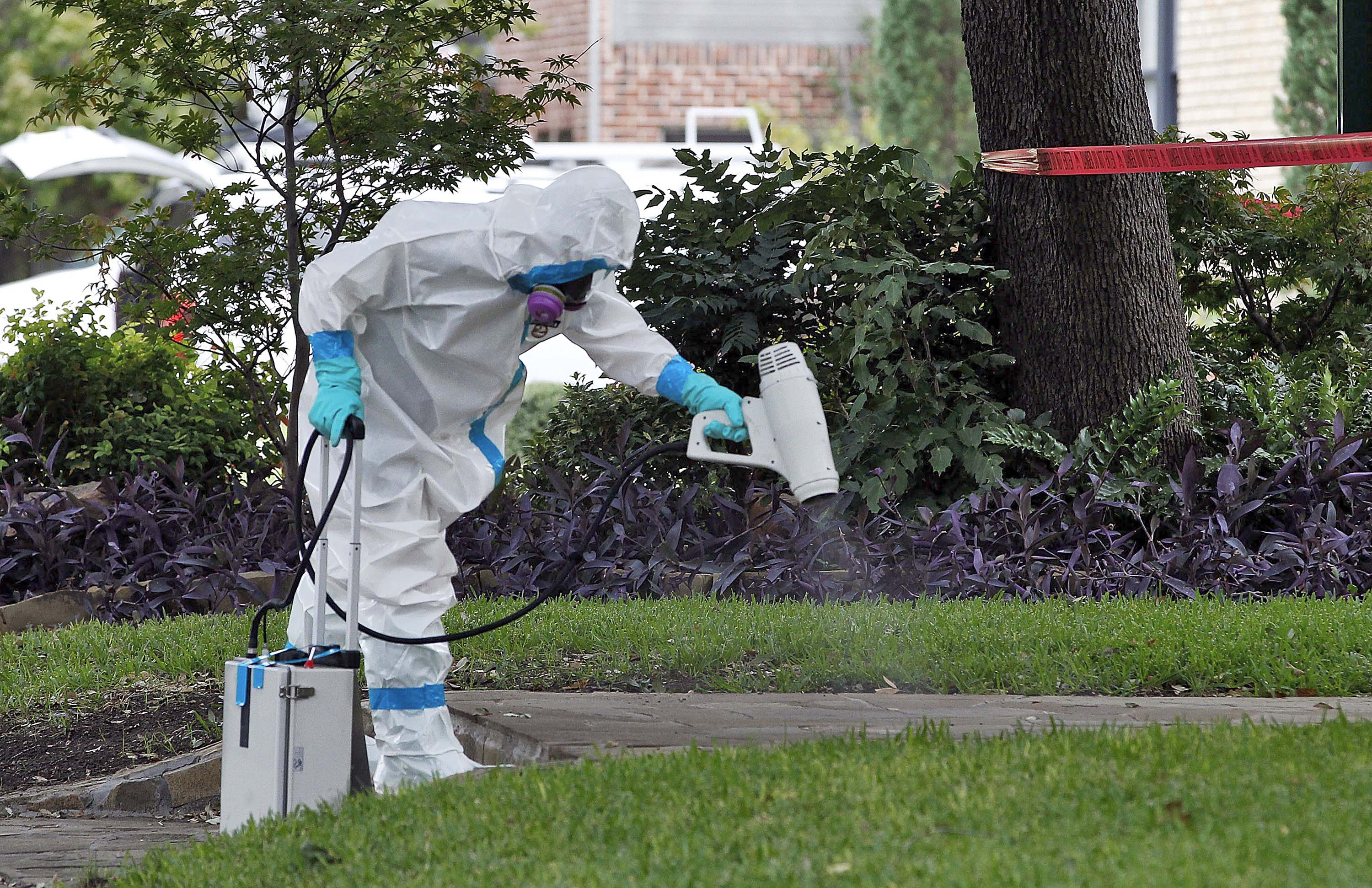 A worker disinfects the sidewalk outside the Dallas home of a nurse diagnosed with the virus (Mike Stone—Getty Images)