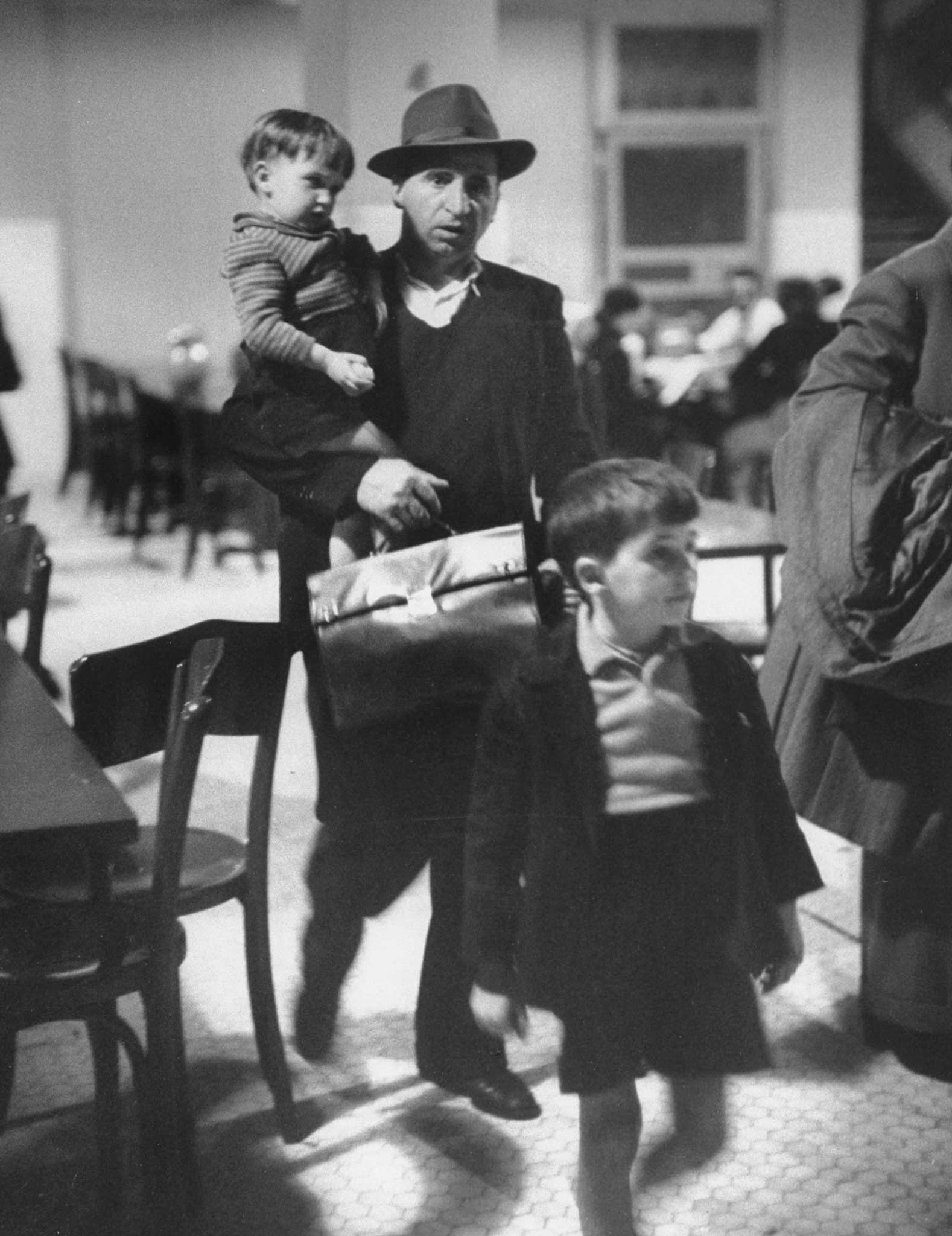 "Antonio Magnani copes with his children and fat briefcase holding his entry papers." Ellis Island, 1950.