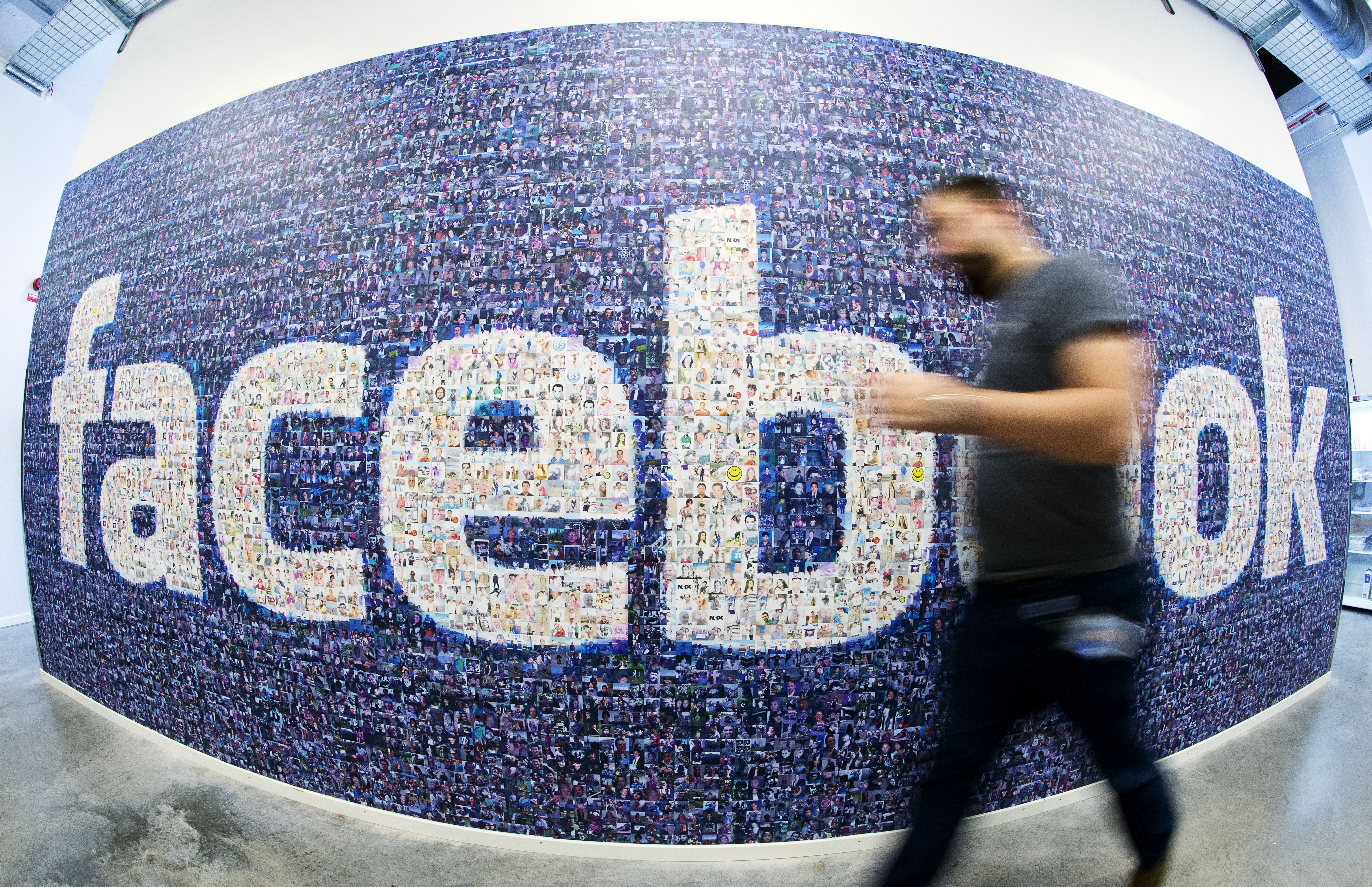 This picture taken with a fisheye lens shows a man walks past a big logo created from pictures of Facebook users worldwide in the company's Data Center, its first outside the US on November 7, 2013 in Lulea, in Swedish Lapland. (JONATHAN NACKSTRAND&mdash;AFP/Getty Images)