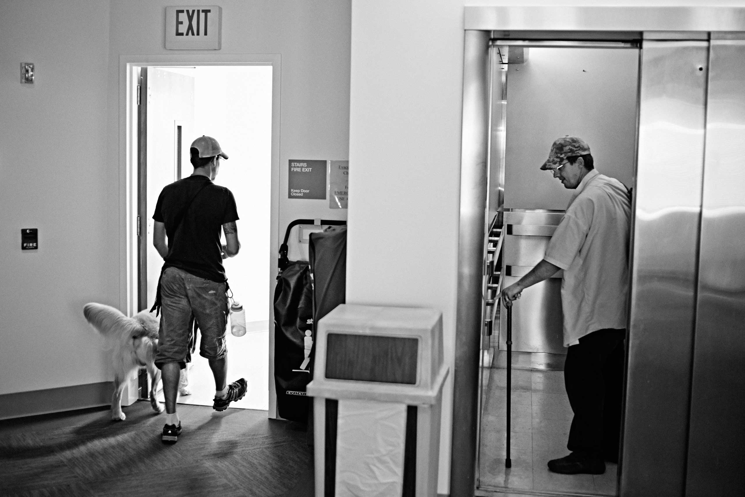 Paul Robicheaux (R) takes the elevator while Joshua JC Brum leads a service dog towards the staircase at the VA’s Menlo Park campus in California, United States on October 3, 2014.
                              
                              US Marine Corps Veteran Paul Robicheaux served with 1st Battalion, 12th Marines at Marine Corps Base Hawaii between 1993 and 1997.
                              
                              US Air Force Veteran Joshua JC Brum served with 99th Air Base Wing, 99th Civil Engineer Squadron, EOD squadron on two tours in Iraq and one in Afghanistan between 2008 and 2011.
                              
                              Paws for Purple Hearts is the first program of its kind to offer therapeutic intervention for Veterans and active-duty military personnel by teaching those with Post-Traumatic Stress Disorder (PTSD) to train service dogs for their comrades with combat-related injuries.
