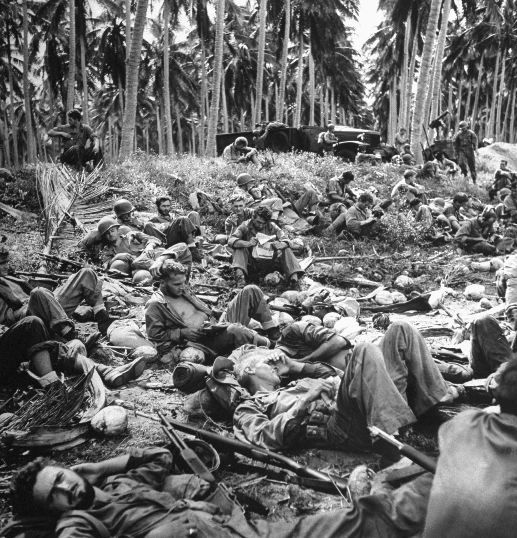 Exhausted U.S. Marines sprawl on the beach while waiting for landing craft to take them off Guadalcanal following four months of fighting the Japanese.