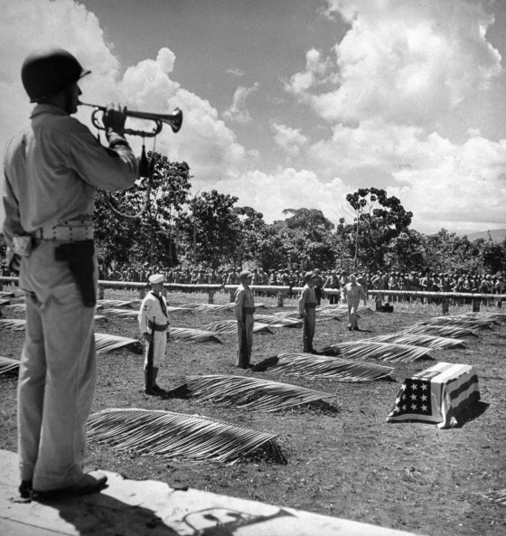 A U.S. Marine on Guadalcanal plays taps during a service for the dead before leaving the island to the Army, 1942.