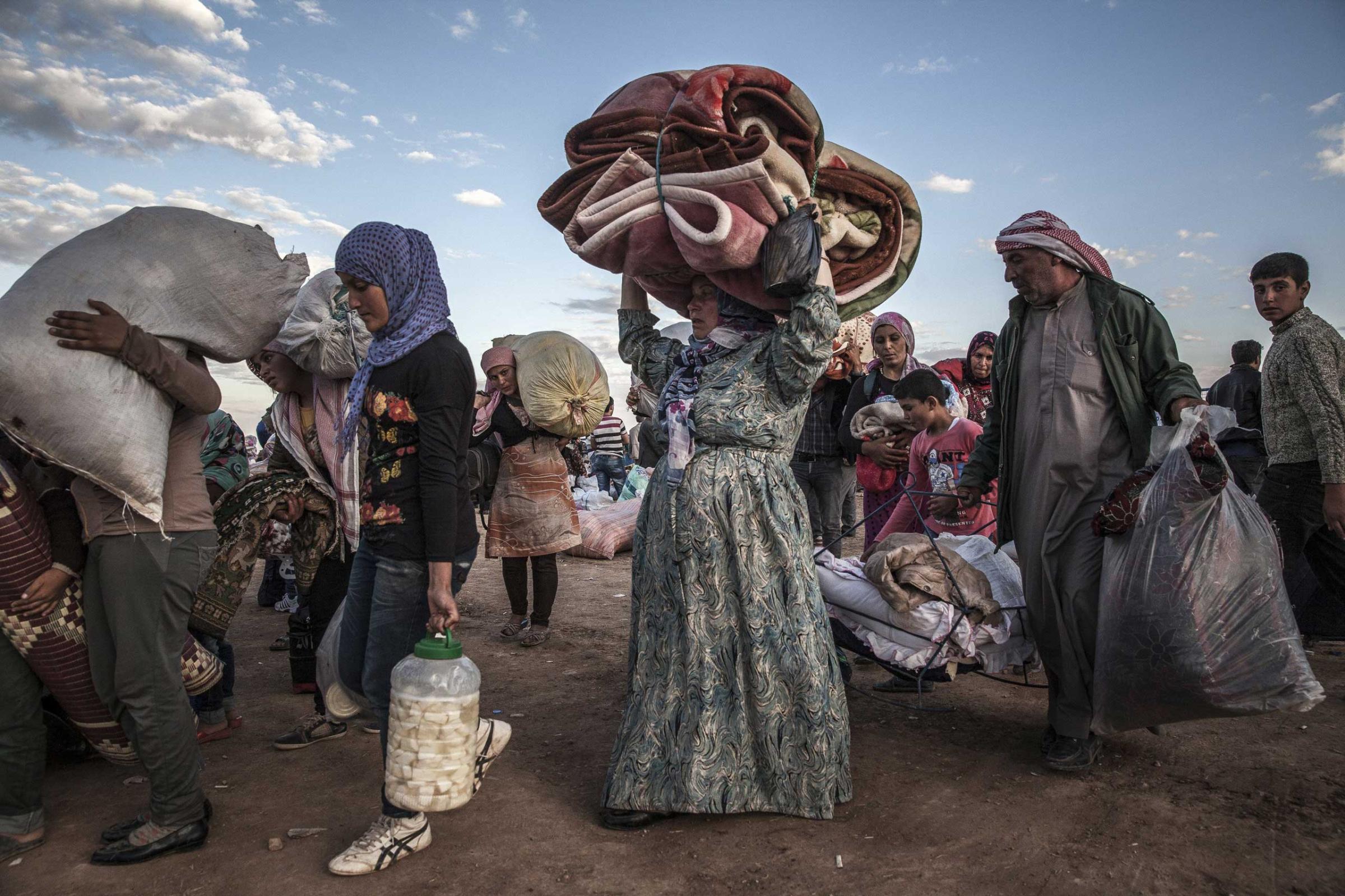 Syrian Kurdish refugees at the Yumurtalik border crossing wait to be taken to shelters elsewhere in Turkey.