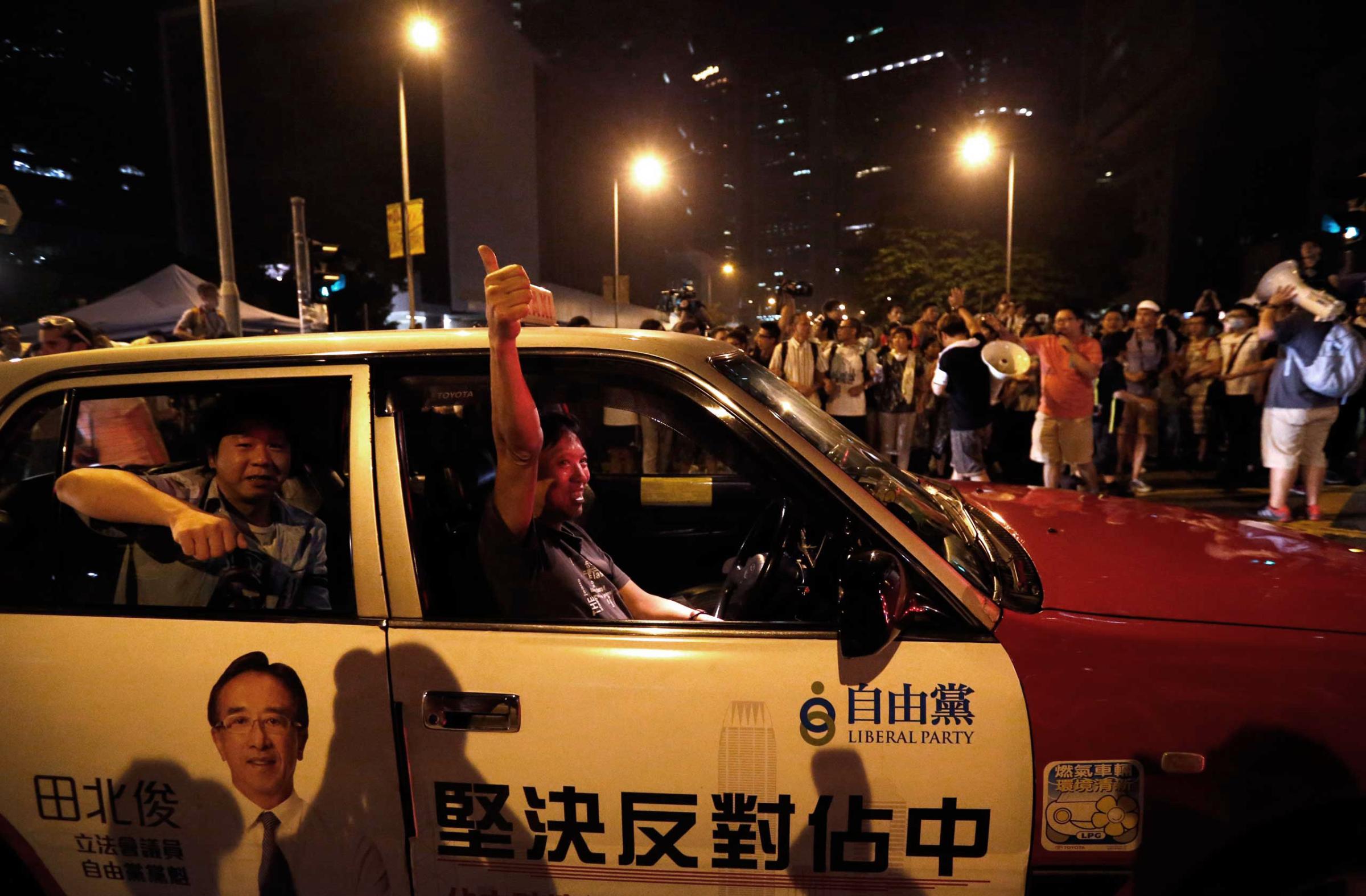 A taxi driver gives a thumbs up to pro-democracy protesters as he drives past the protest site in front of Hong Kong's Chief Executive Leung Chun-ying's office, Oct. 3, 2014 in Hong Kong.