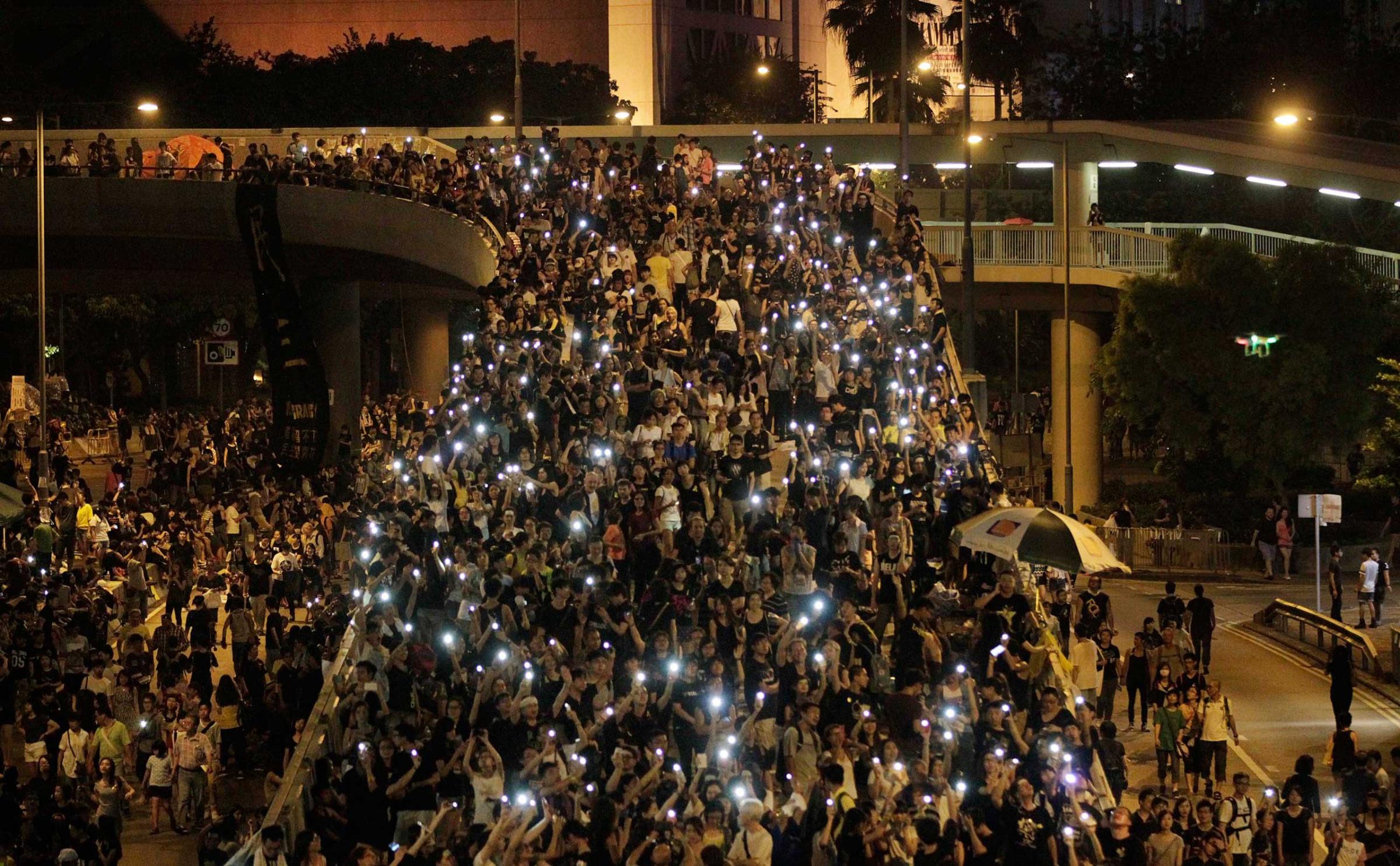 Tens of thousands of pro-democracy demonstrators, some waving lights from mobile phones, fill the streets in the main finical district of Hong Kong, Oct. 1, 2014.