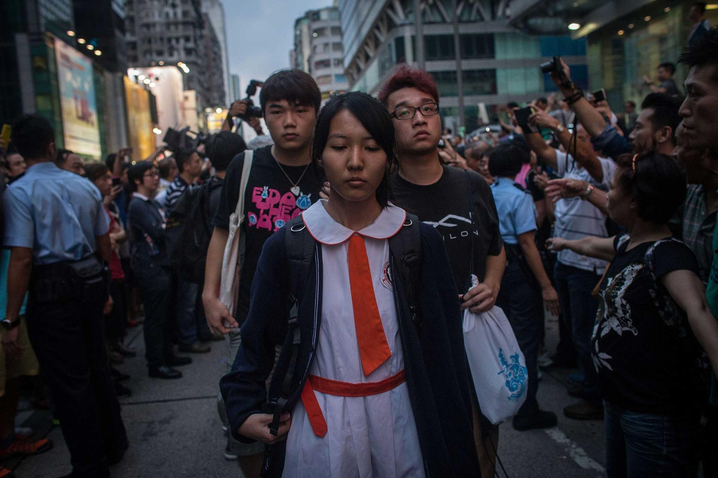 Students and pro-democracy activists leave the protest site as local police hold back local residents and pro-government supporters on Oct. 3, 2014 in Mong Kok, Hong Kong.