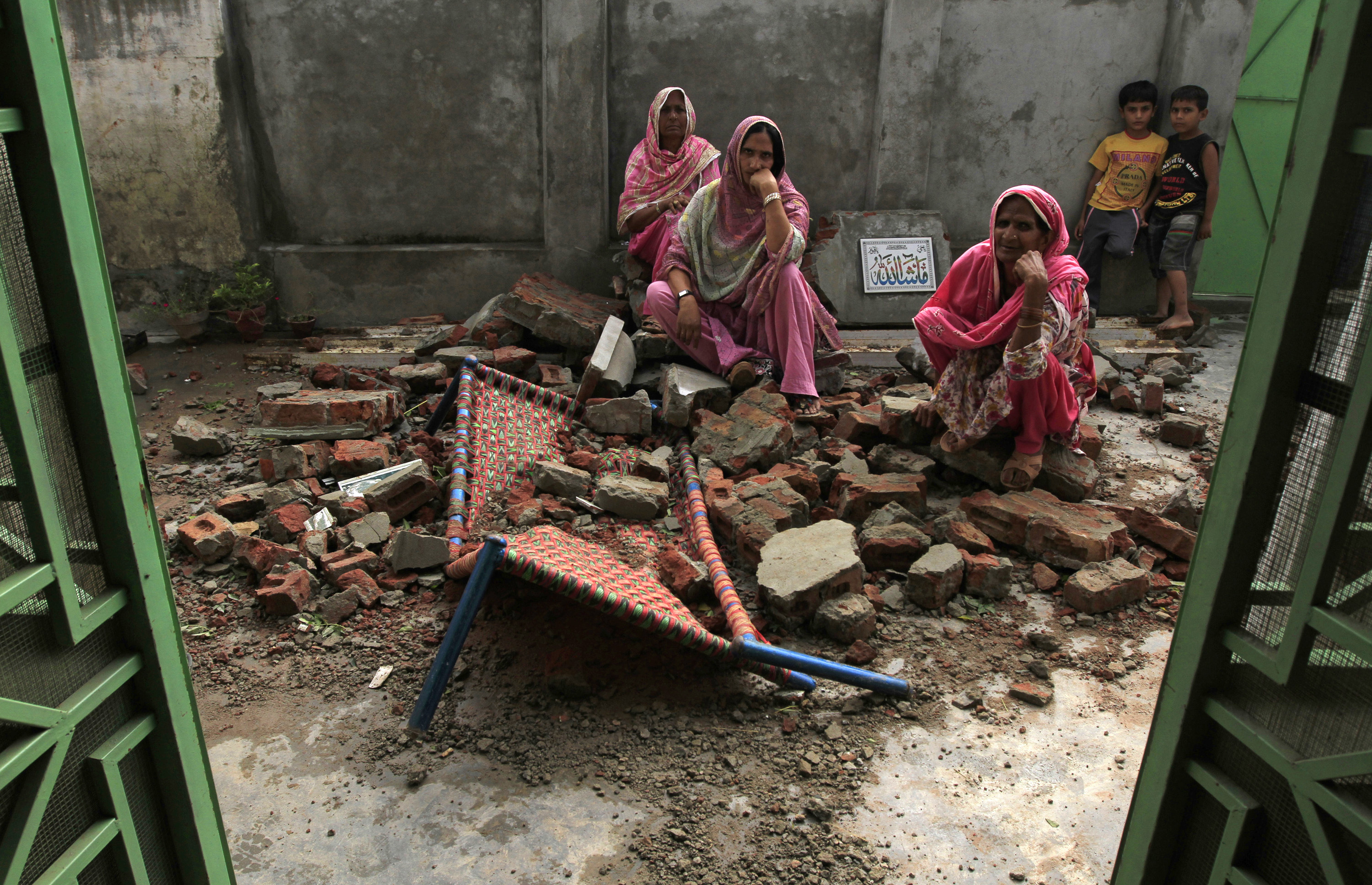 Villagers sit on the debris of their house after it was damaged during the recent exchange of fire between Pakistan and India at the Pakistani border town of Dhamala Hakimwala