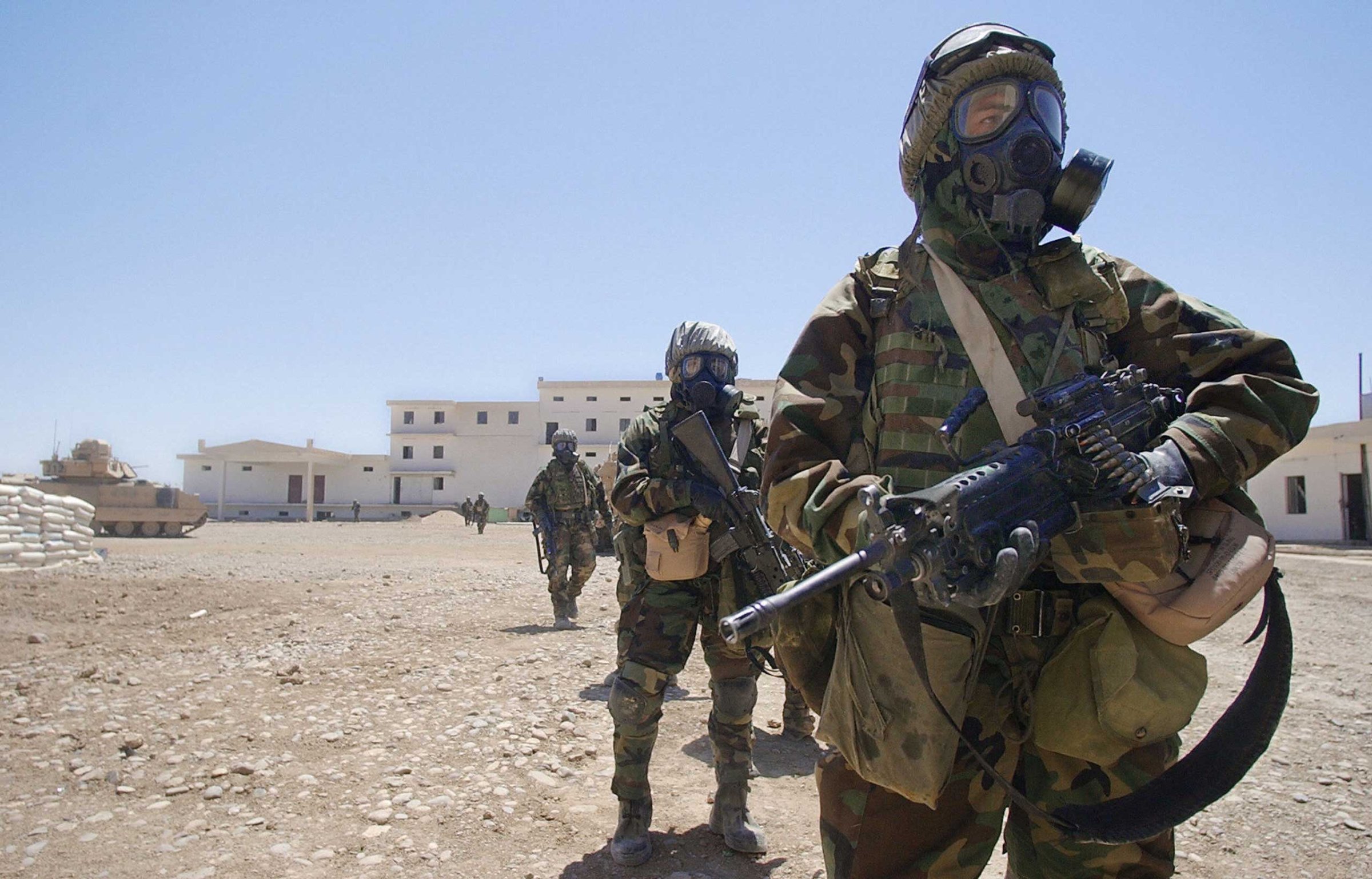 US Army soldiers wearing their full chemical protection suits walk inside the courtyard of an industrial complex they secured which they thought was a possible site for weapons of mass destruction in the central Iraqi town of Baquba in May 2003.
