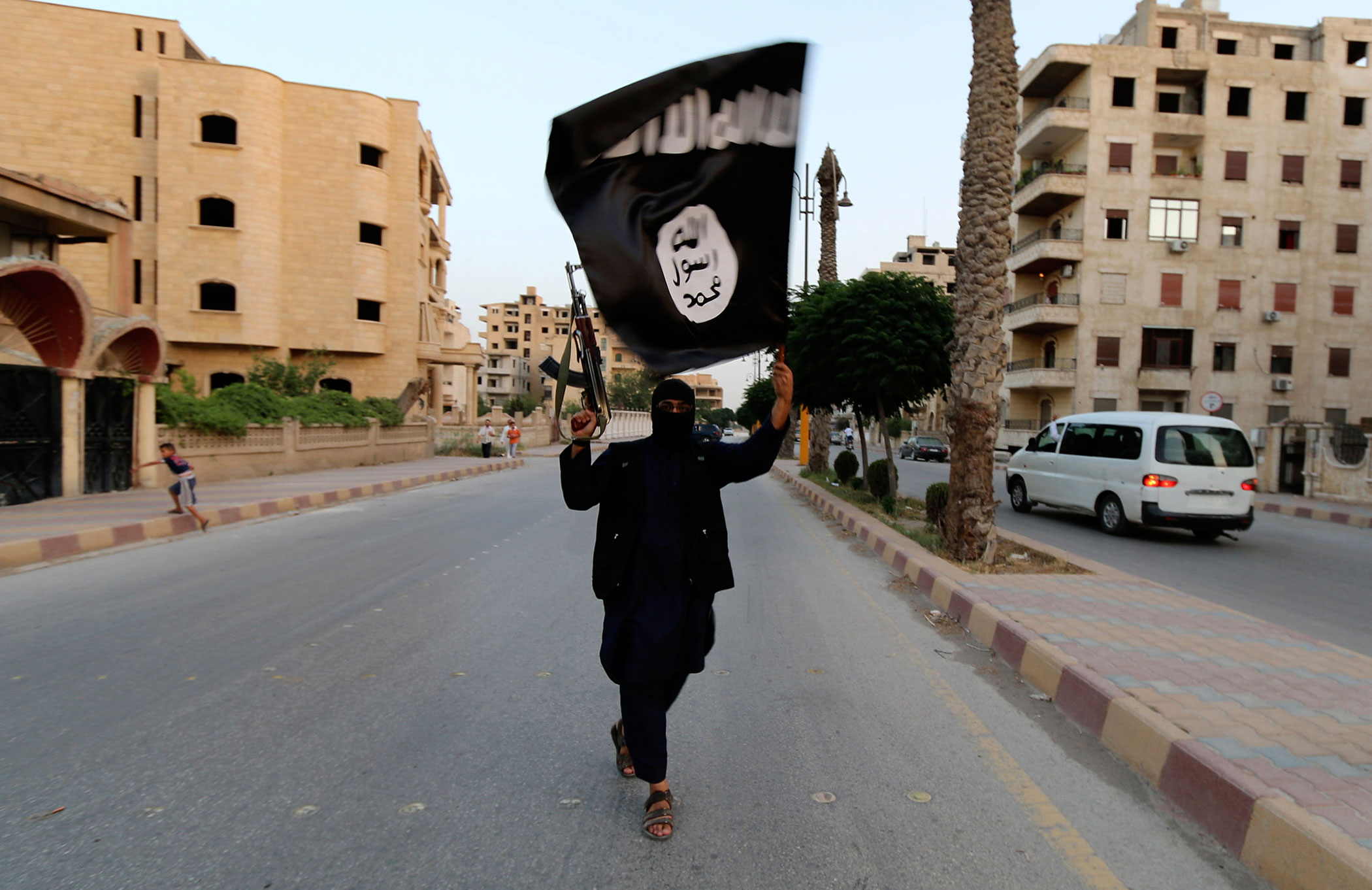 A member loyal to ISIS waves an ISIS flag in Raqqa, Syria, on June 29, 2014 (Reuters)