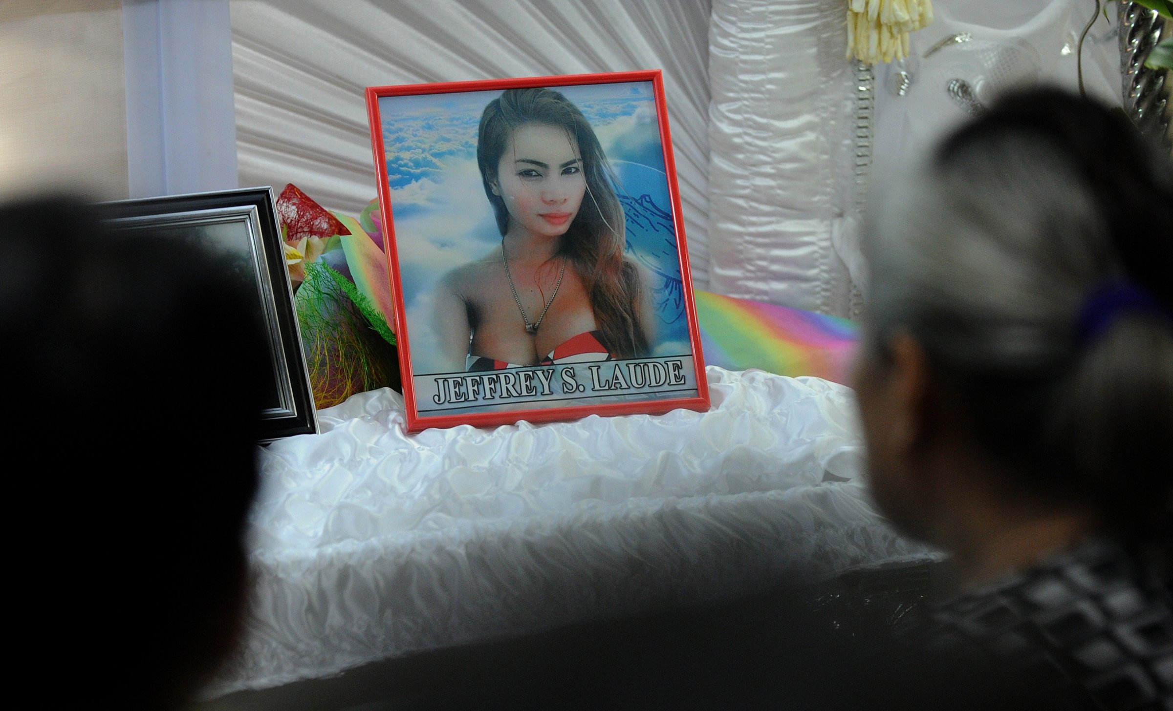 Friends and relatives of Filipino transgender resident Jeffrey Laude look on alongside his coffin and photograph in the northern Philippine city of Olongapo on Oct. 14, 2014.