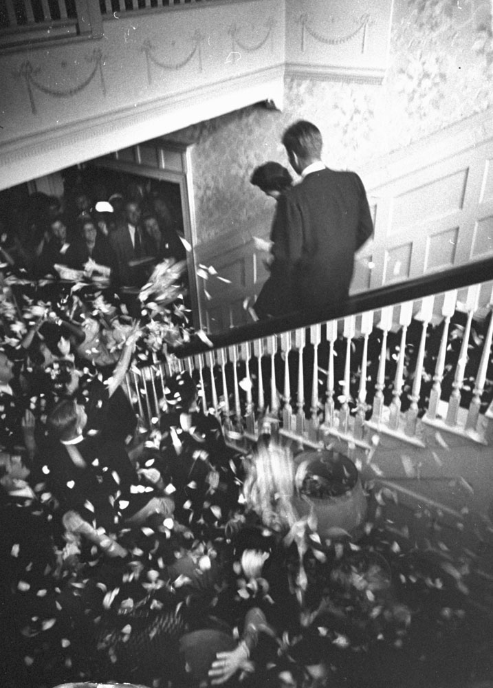 "Off for honeymoon in Acapulco, Mexico, the bride and bridegroom leave the wedding reception amid a shower of rose-petal confetti and rice."