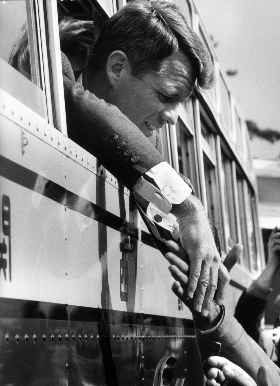 Robert Kennedy shakes hands from a train window, Japan, 1962.