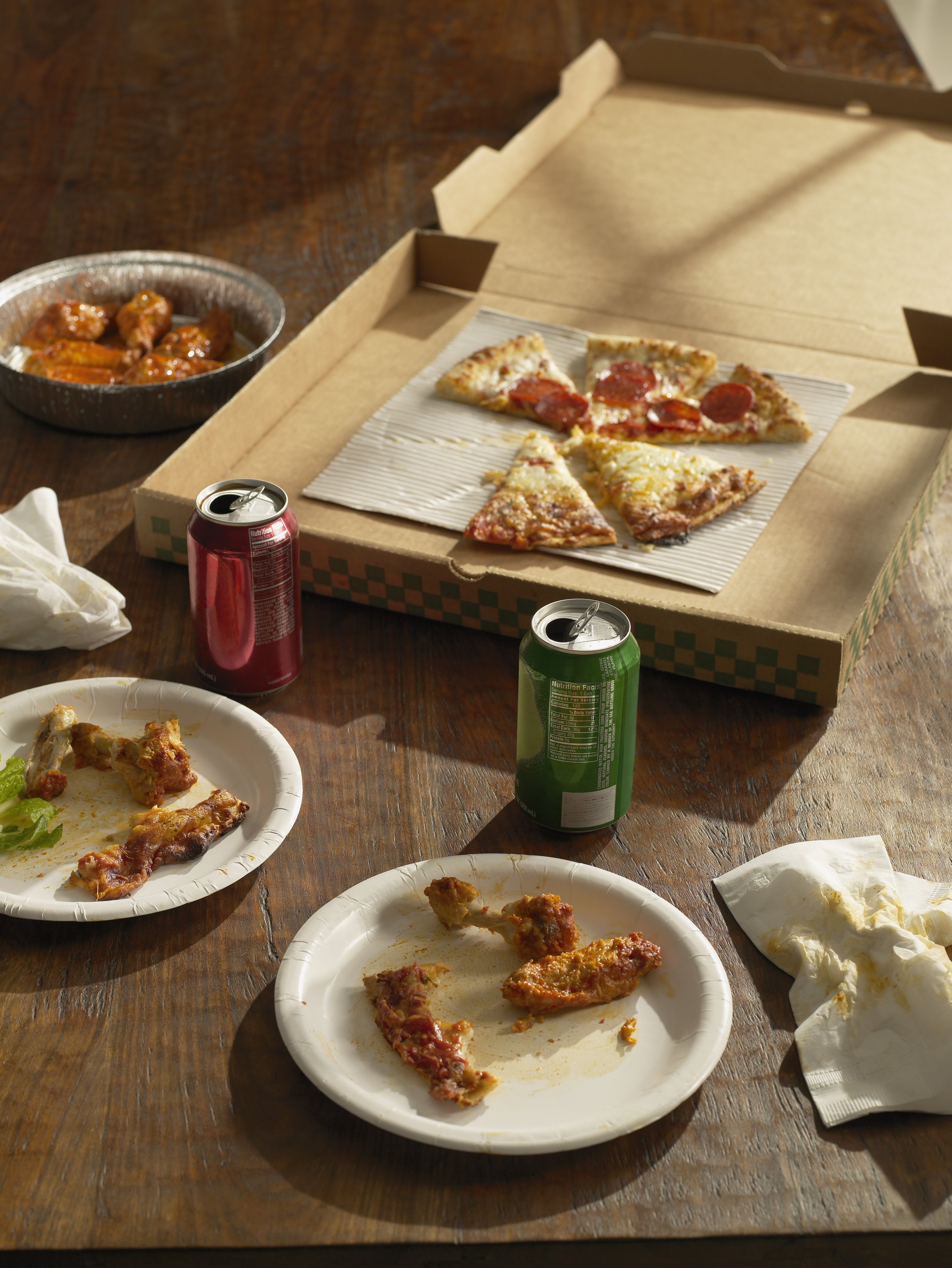 Half-eaten pizza , Buffalo wings and sodas