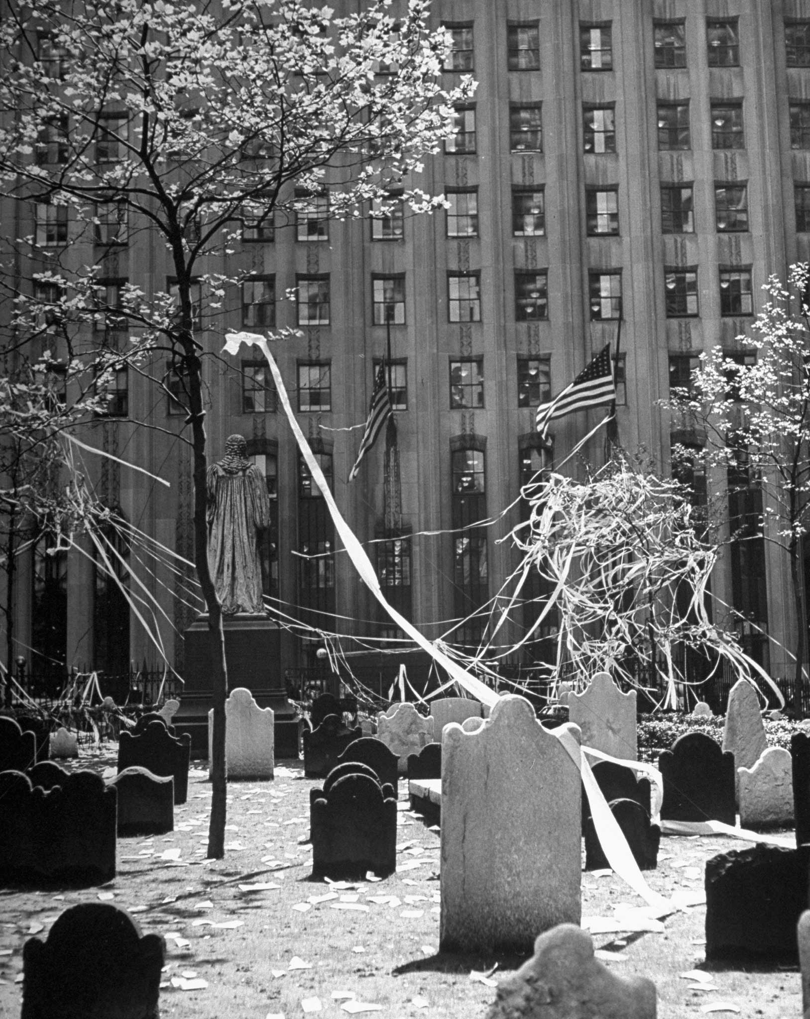 Tangled streamers and confetti thrown by people celebrating the end of the war in Europe litter headstones and the grounds of Trinity Church's venerable cemetery at the foot of Wall Street, 1945.